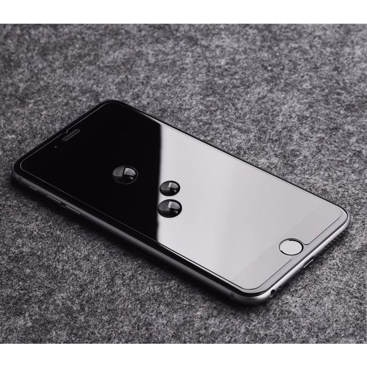 Un smartphone avec des gouttes d'eau sur l'écran est posé sur une surface grise. L'écran du téléphone est noir et réfléchissant.