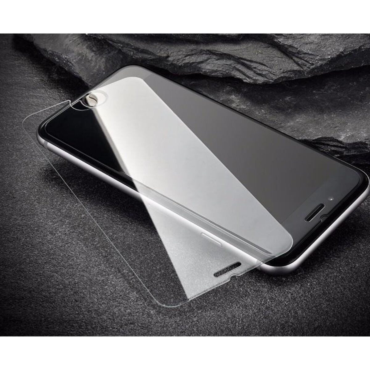Un smartphone avec un protecteur d'écran partiellement appliqué. Le téléphone repose sur une surface sombre et texturée.