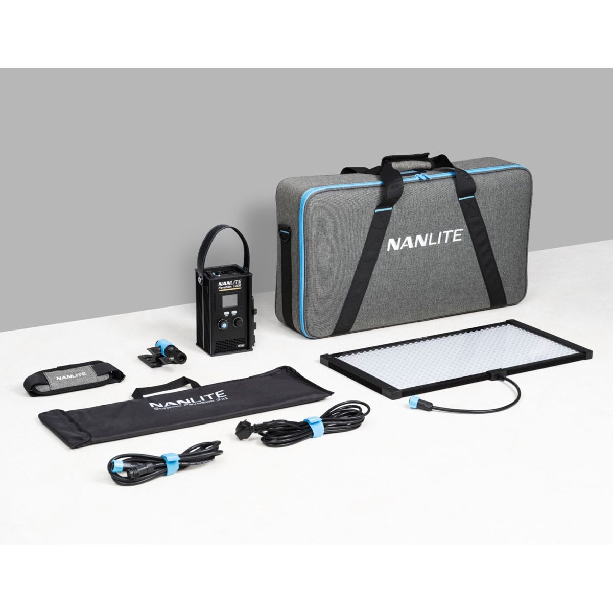 Un kit d'éclairage Nanlite est affiché. Il comprend un sac de transport, un panneau lumineux, une unité de contrôle, des câbles et des accessoires, le tout sur une surface blanche.