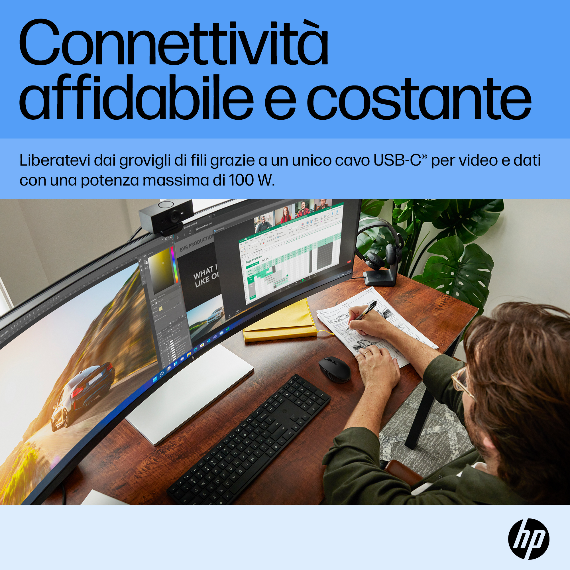 Mężczyzna pracuje przy biurku z zakrzywionym monitorem. Nad monitorem znajduje się kamera internetowa. Na biurku znajduje się klawiatura i mysz.