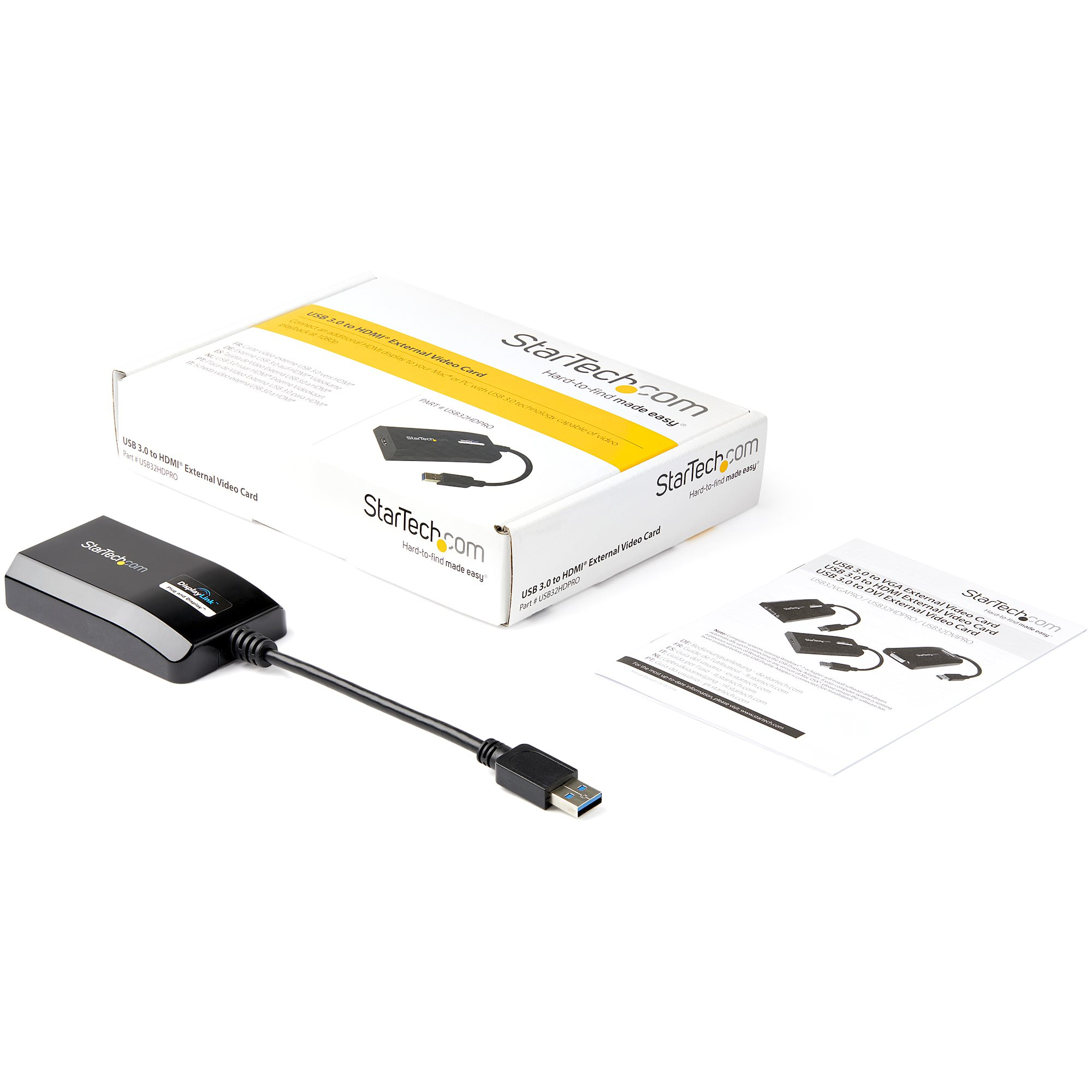 Adaptador USB a HDMI negro, caja y manual sobre superficie blanca. Se ve la marca StarTech.com.
