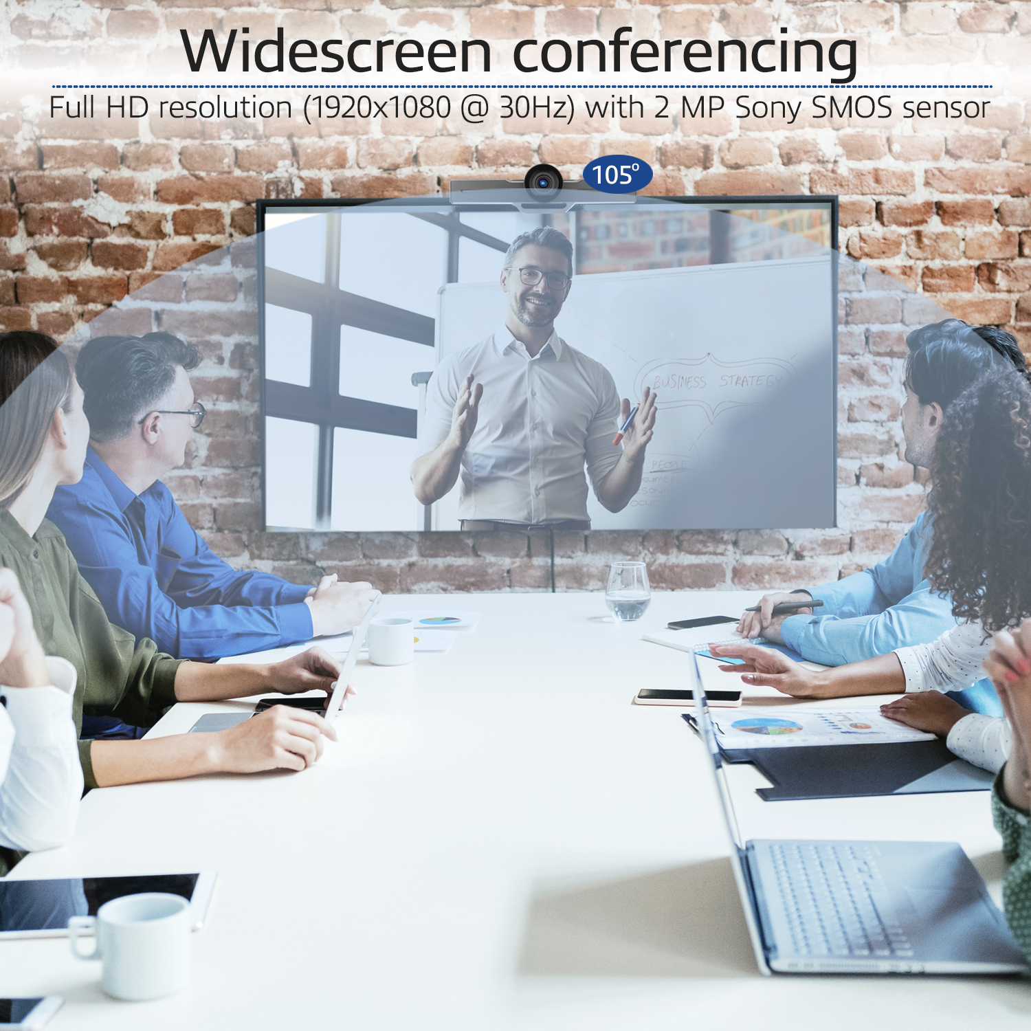 Ein Team konferiert und schaut sich eine Präsentation auf einem Bildschirm an. Ein Mann präsentiert auf dem Bildschirm. Ein Tisch mit Laptops und Dokumenten.