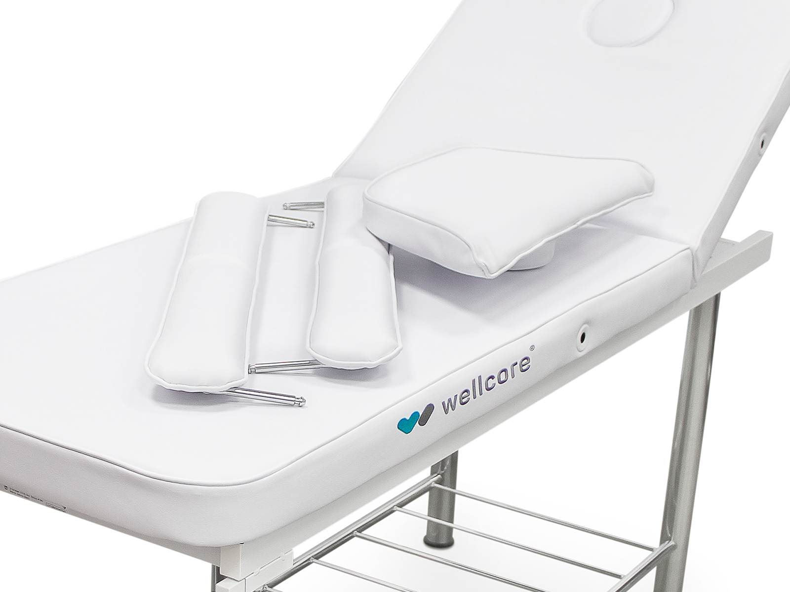 Una camilla de masaje blanca con accesorios, incluyendo almohadas y reposabrazos. La mesa tiene un logo Wellcore.