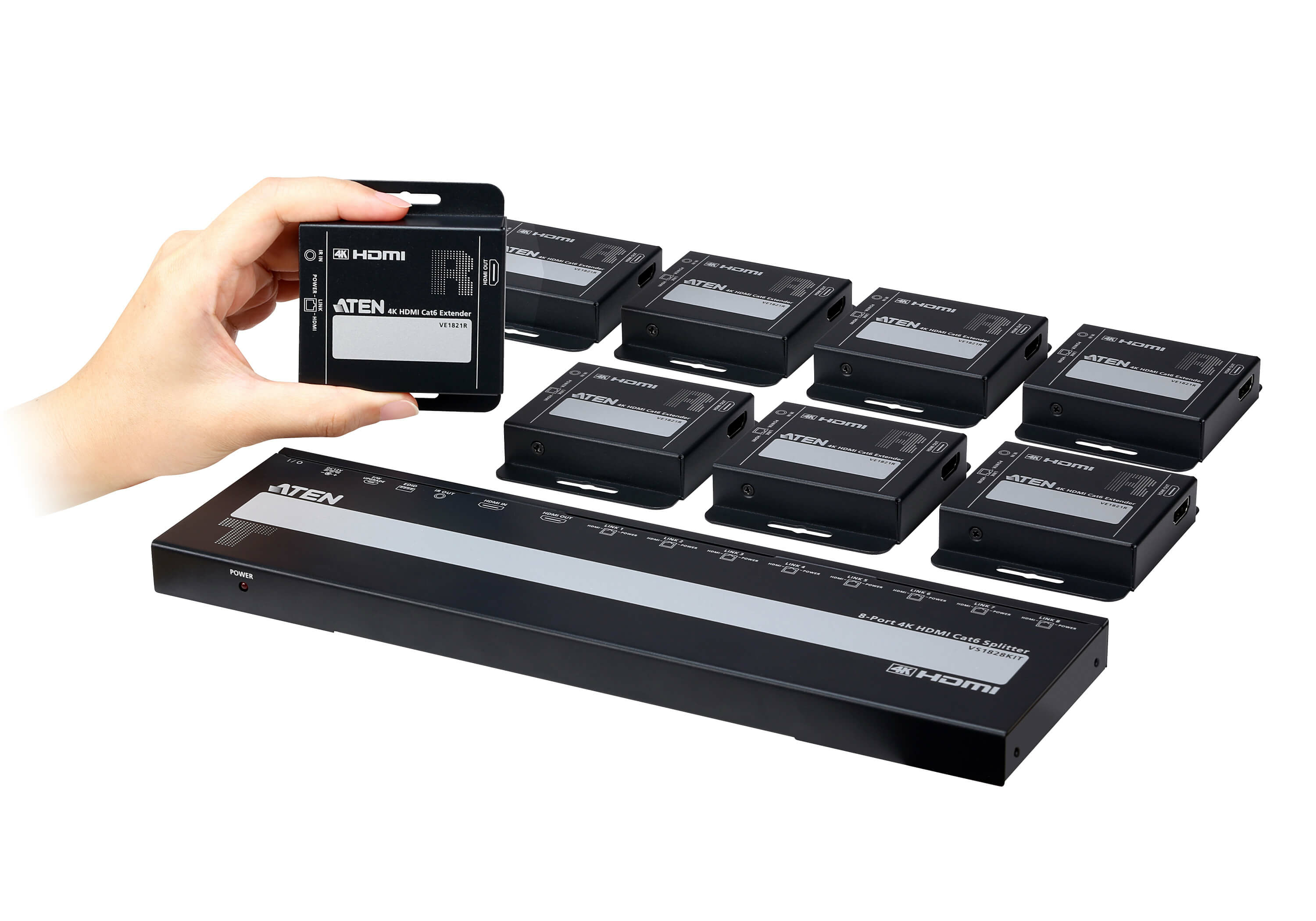 Une main tient un extendeur HDMI noir. Plusieurs extendeurs similaires et un splitter sont disposés sur fond blanc.