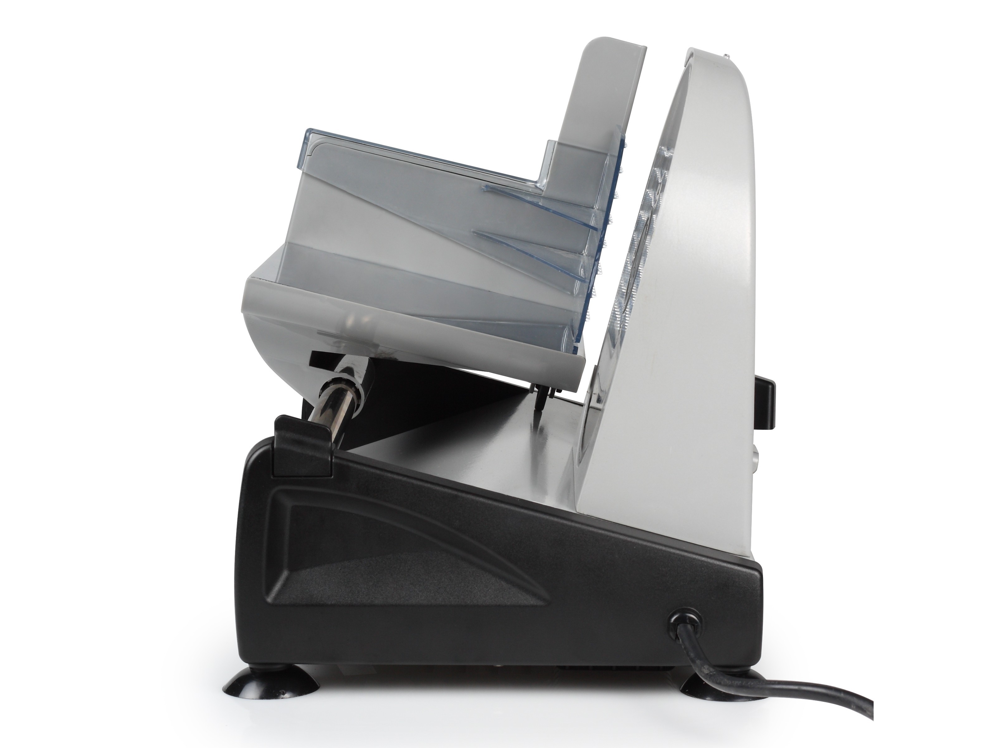 Une trancheuse à aliments argentée et noire. Elle est sur une surface blanche, avec un plateau en plastique transparent.