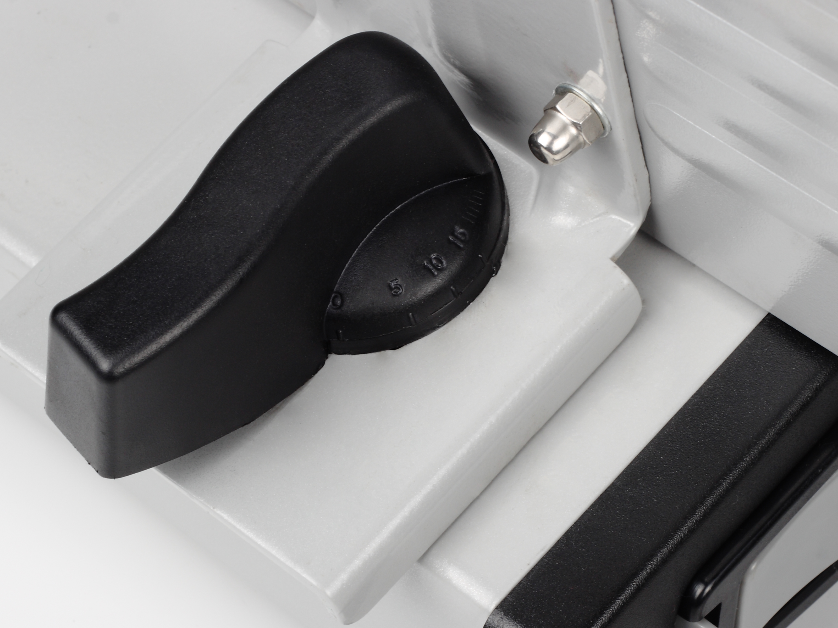 Gros plan d'une trancheuse avec une poignée noire, un boulon argenté et une surface blanche et grise.