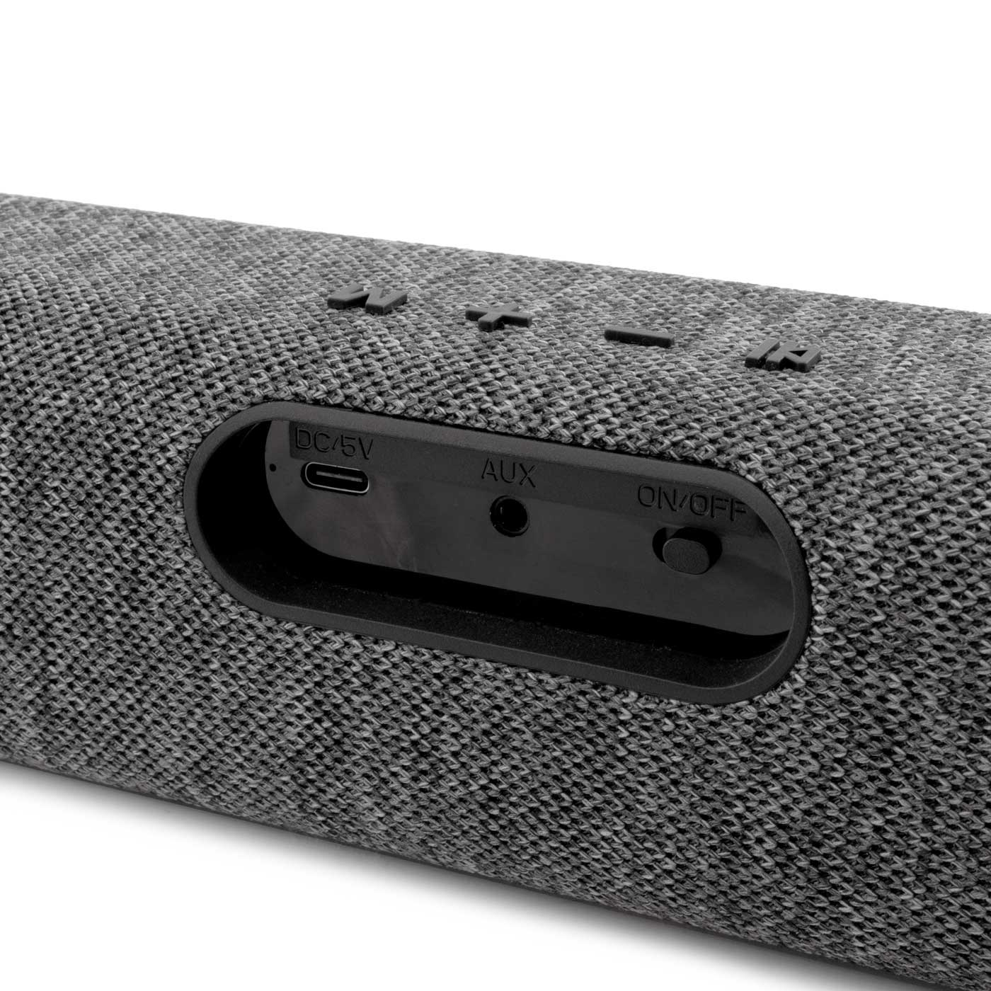 Primer plano de un altavoz gris con botones y puertos. Incluye DC/5V, AUX y ON/OFF. El altavoz tiene una superficie texturizada.