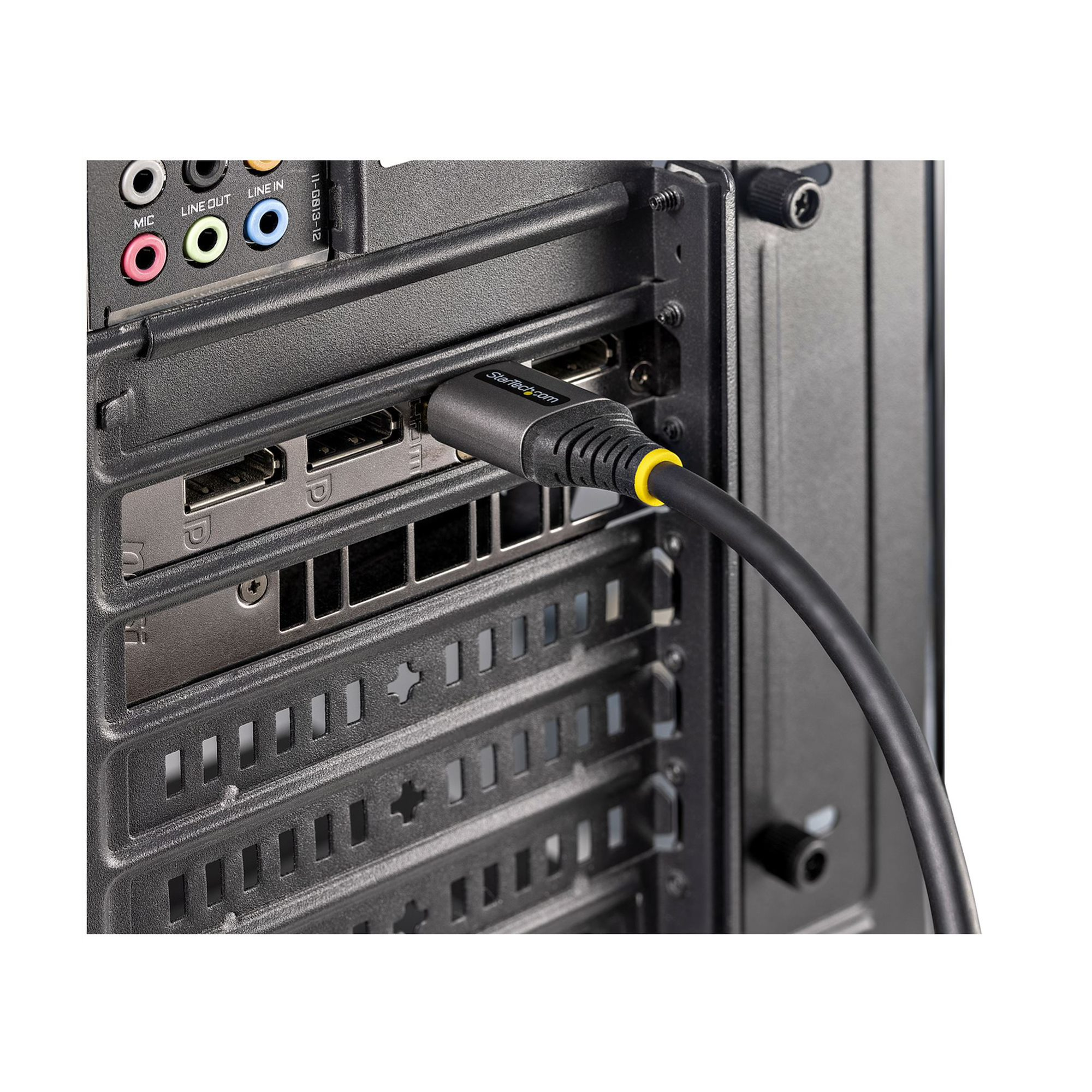 Panel trasero de una computadora con un cable enchufado a un puerto. El cable tiene un anillo amarillo y la marca StarTech.