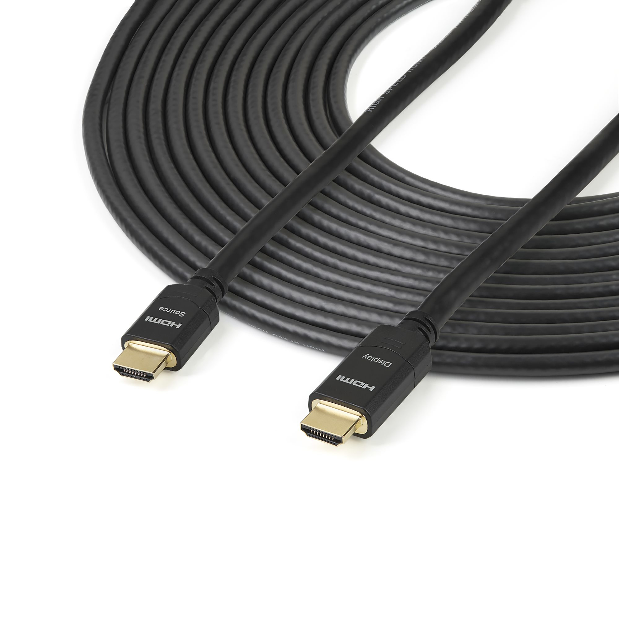 Un cable HDMI negro sobre una superficie blanca. El cable está enrollado en el fondo, con conectores etiquetados como 'HDMI Source' y 'Display'.