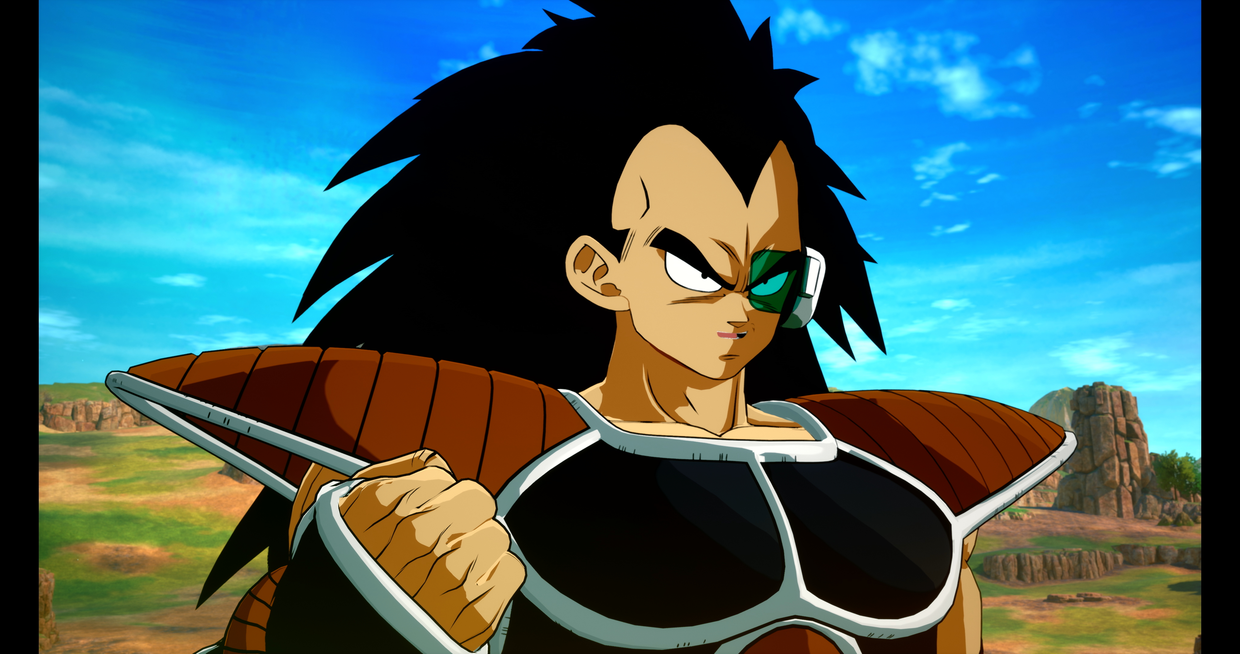 Un guerriero Saiyan con capelli neri a punta e armatura, in piedi contro un cielo blu con nuvole e un paesaggio.