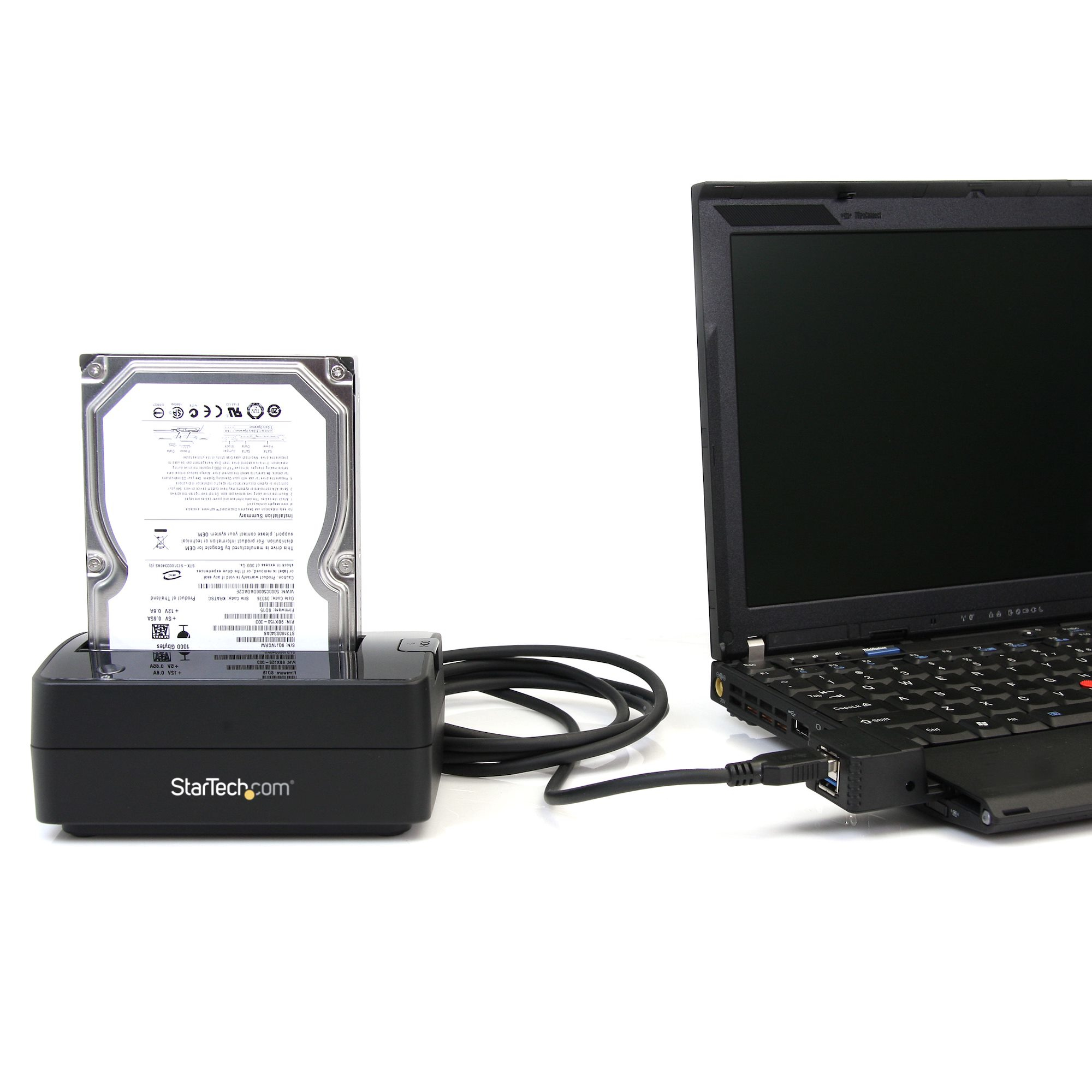 Eine Festplatte ist neben einem Laptop angedockt. Ein Kabel verbindet die Dockingstation mit dem USB-Anschluss des Laptops.