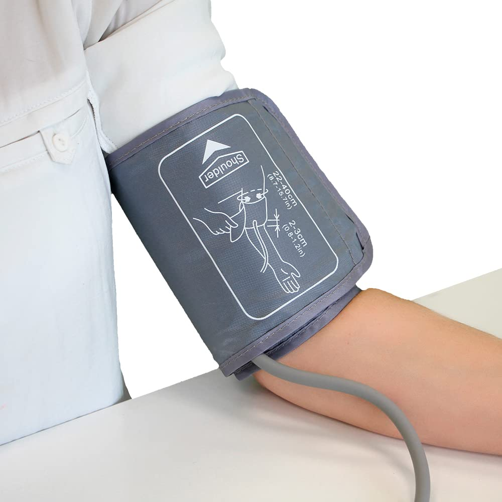 Brazo con manguito de presión arterial. Manguito gris en el brazo. Ropa y mesa blancas en el fondo. Un tubo gris está conectado al manguito.
