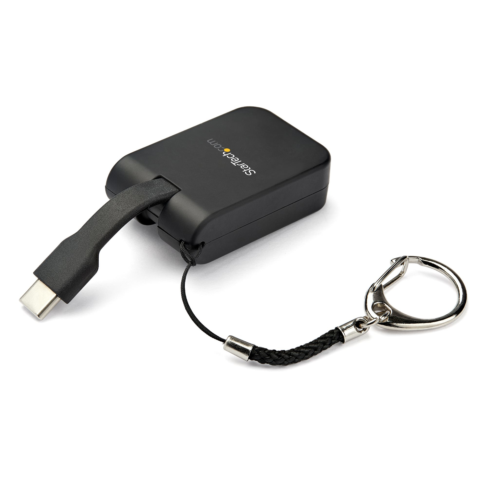 Un adaptador USB-C negro StarTech con un llavero adjunto sobre una superficie blanca.