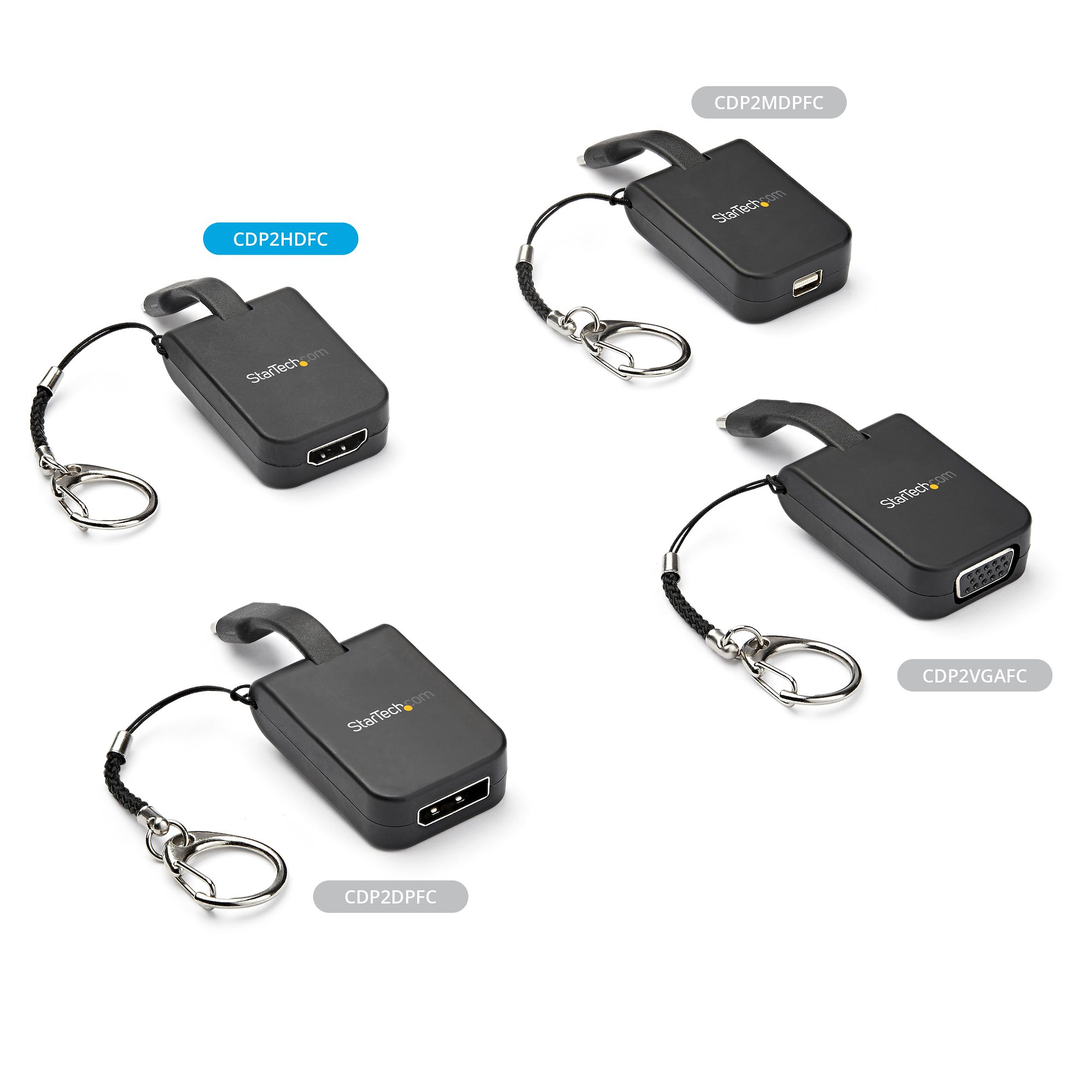 Cuatro adaptadores StarTech negros con llaveros, sobre una superficie blanca. Cada uno tiene un puerto diferente: HDMI, USB, VGA y DisplayPort.