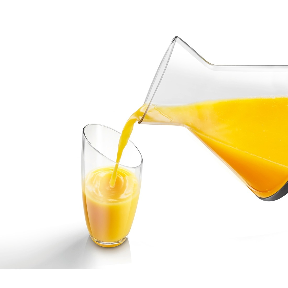 Una jarra vierte jugo de naranja en un vaso. El vaso está parcialmente lleno. Fondo blanco.