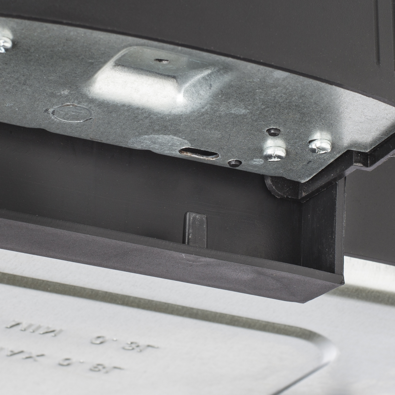 Close-up of metal and black plastic components. Screws and stamped text are visible. The image has a technical look.