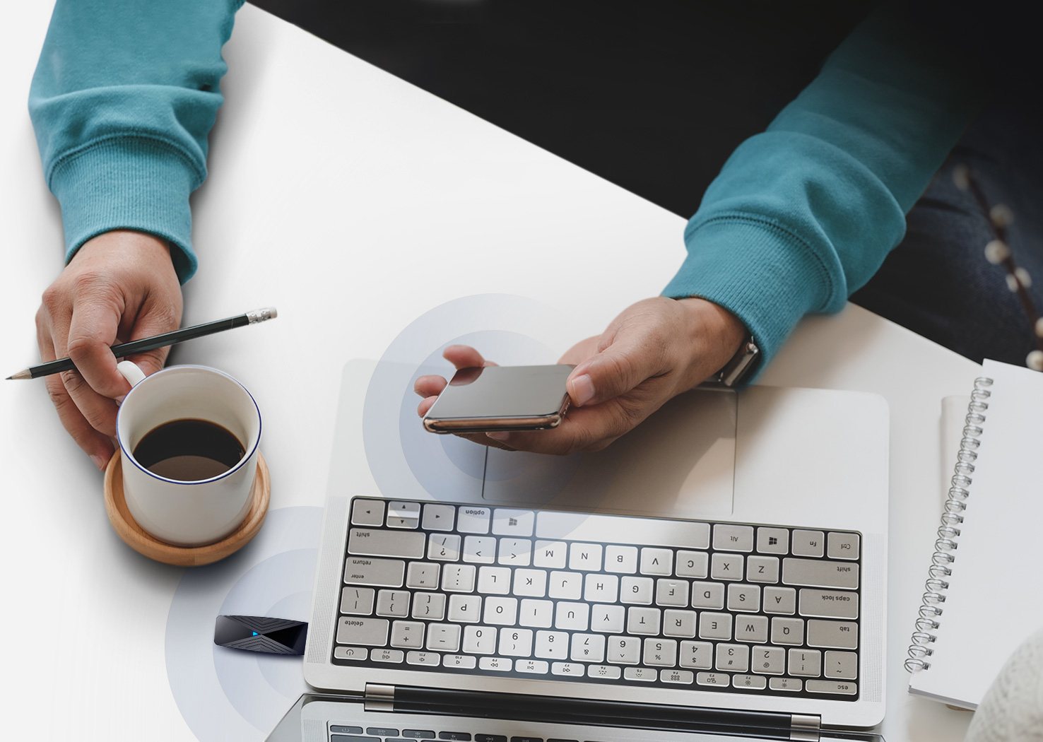 Osoba korzystająca z laptopa i smartfona, z filiżanką kawy i notatnikiem.