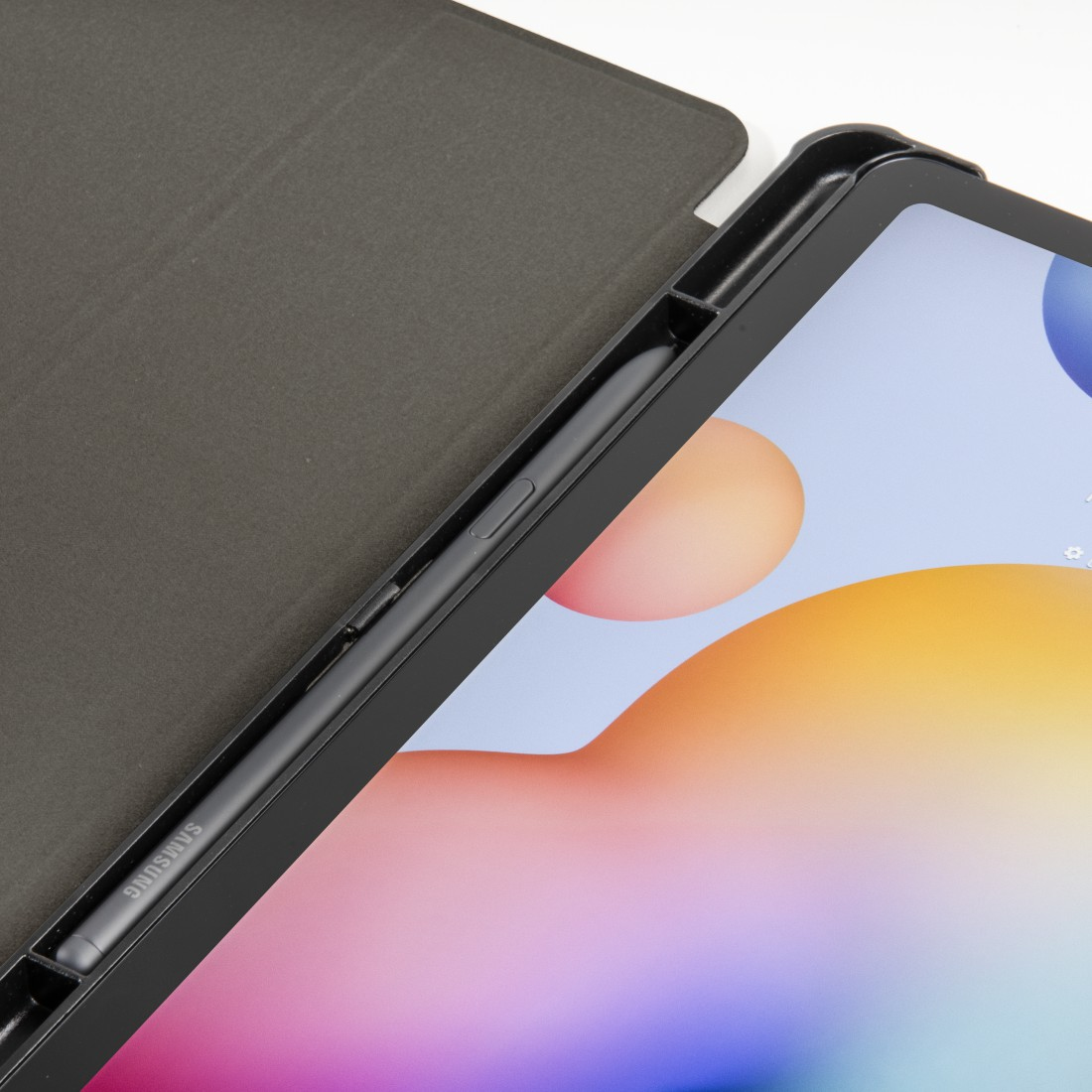 Una tableta con funda negra y lápiz óptico. La pantalla muestra formas coloridas. La funda está abierta, mostrando la pantalla.