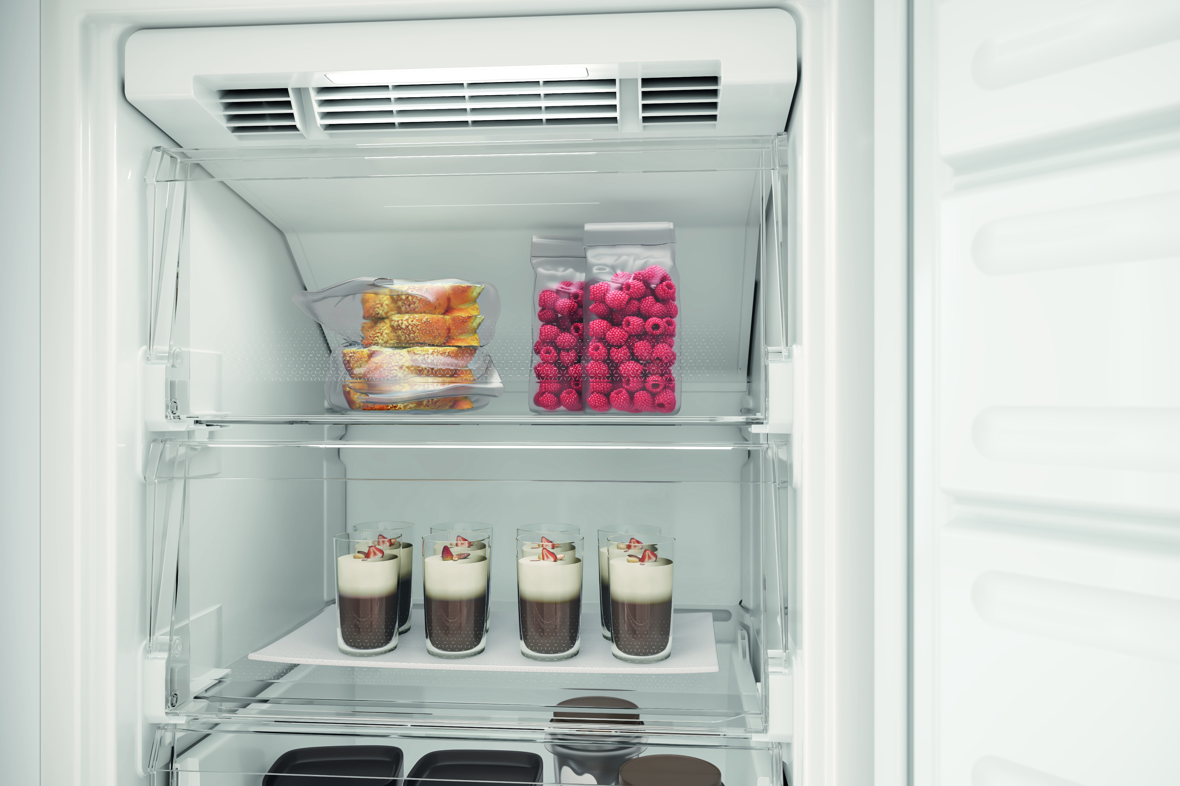 Dentro de un refrigerador, se ven bolsas de plástico con comida y postres en vasos. También se ven frambuesas.