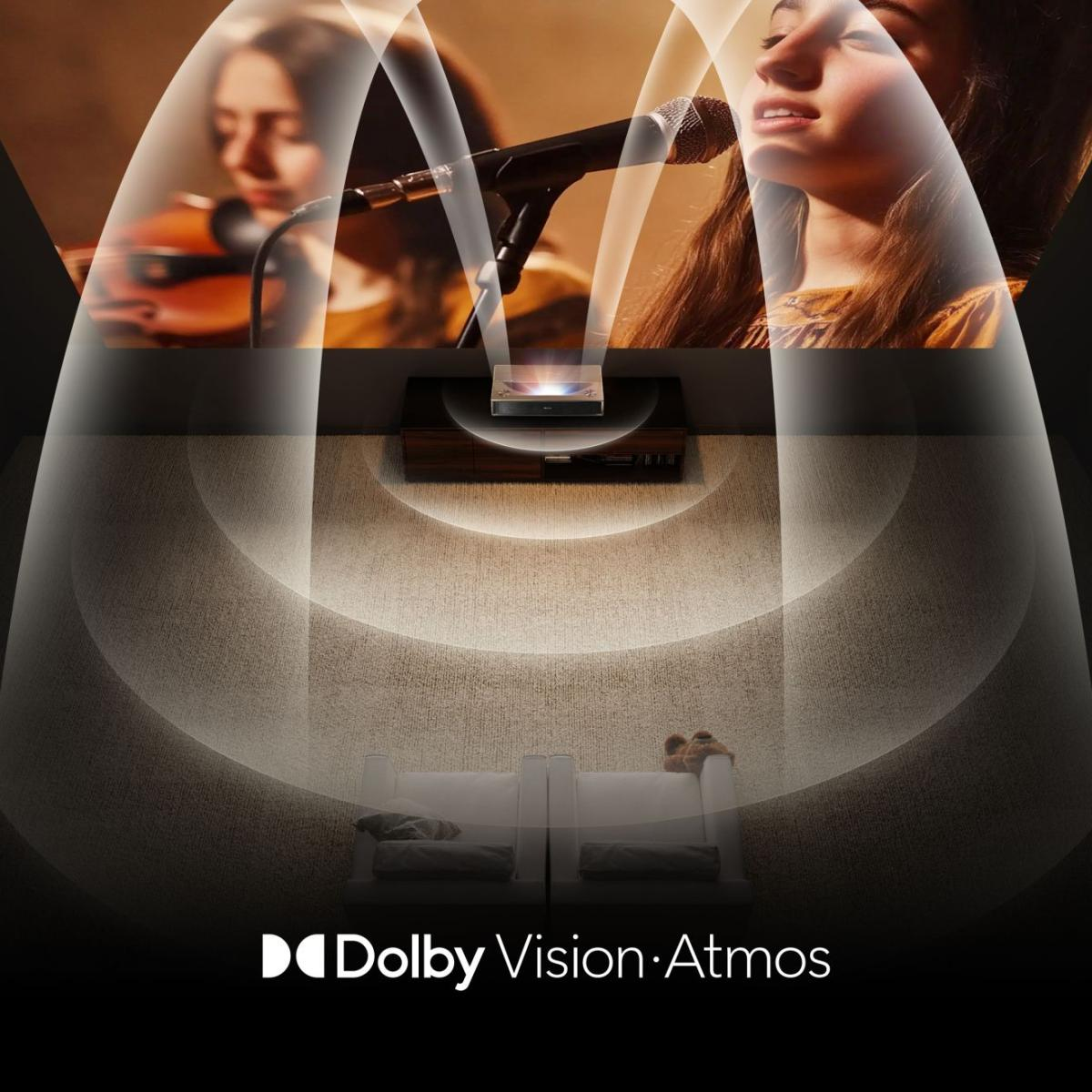 Un projecteur affiche une scène de concert. Des ondes sonores émanent, montrant le logo Dolby Vision Atmos en dessous. Deux canapés blancs au premier plan.