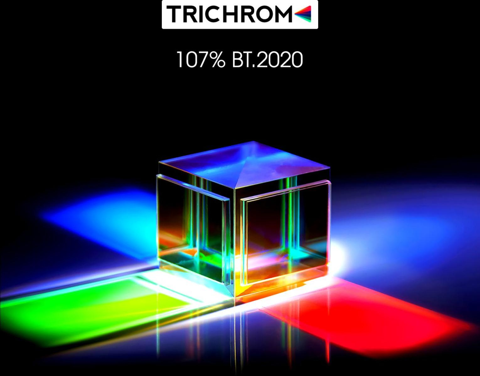 Ein Glaskubus bricht Licht und erzeugt farbige Strahlen. Oben steht 'TRICHROM', darunter '107% BT.2020'.