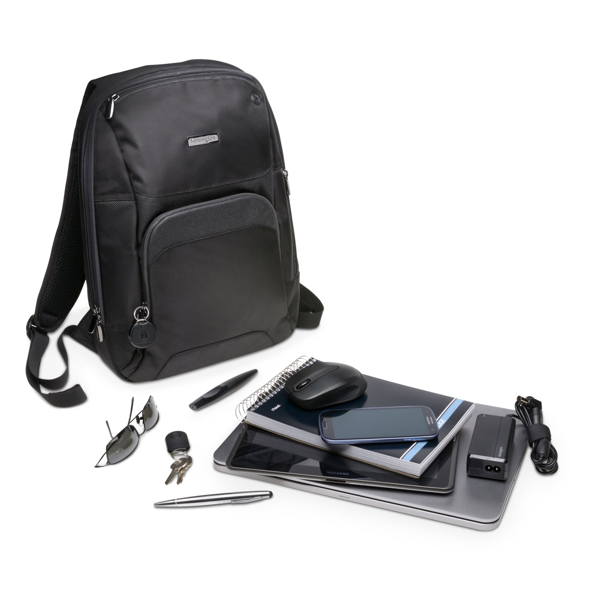 Schwarzer Rucksack, Laptop, Tablet, Telefon, Maus, Sonnenbrille, Schlüssel, Stifte und Ladegerät auf weißem Hintergrund.