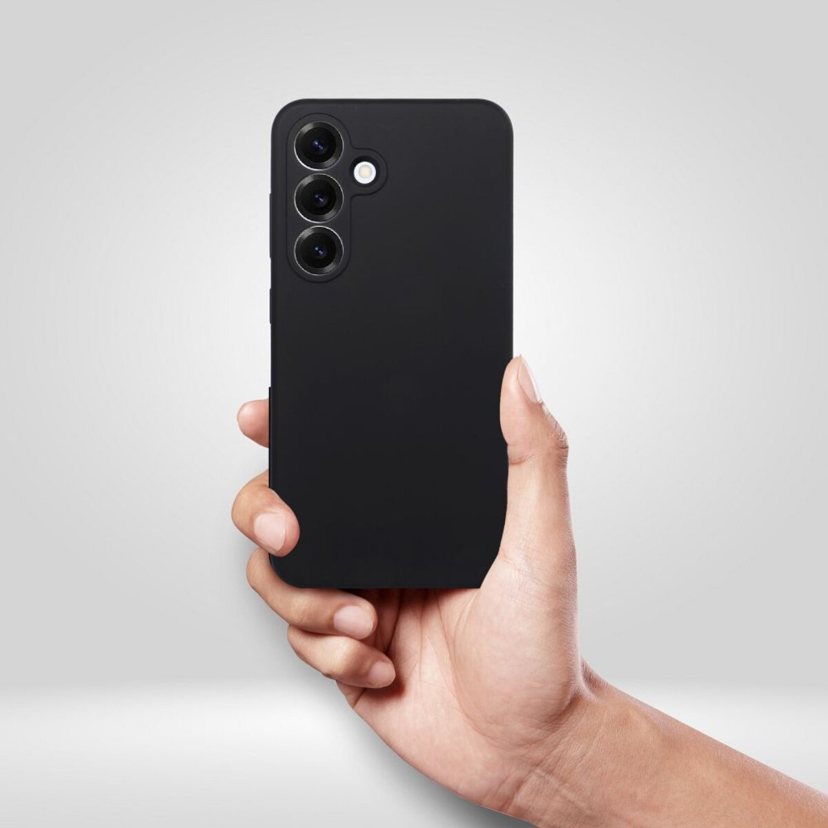 Eine Hand hält ein schwarzes Smartphone mit drei Kameras. Das Telefon ist zentriert, vor einem weiß-grauen Hintergrund.