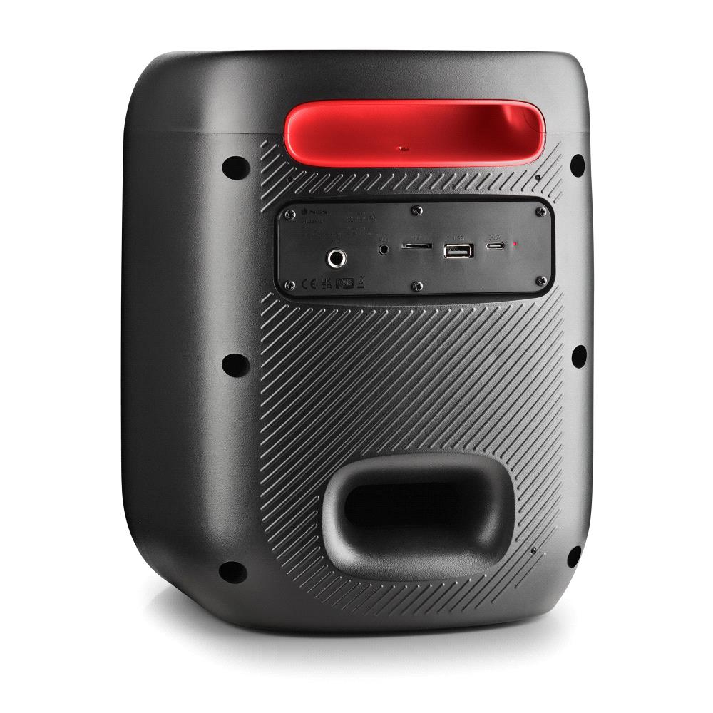 Un altavoz negro con asa roja. Tiene un panel con entradas y un puerto de bajos grande. El altavoz está sobre una superficie blanca.