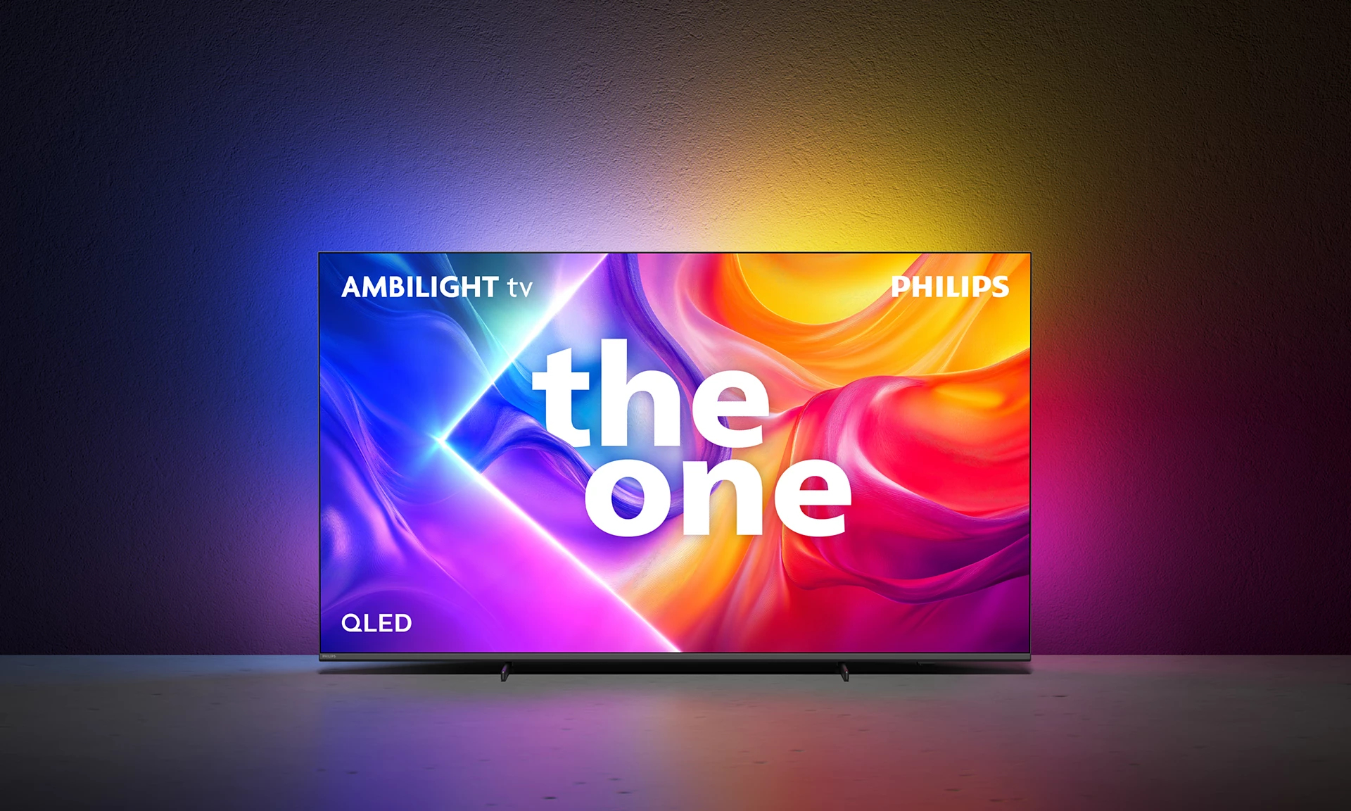 Telewizor Philips Ambilight. Ekran wyświetla 'the one' z kolorowym oświetleniem otoczenia. Tło to gradient.