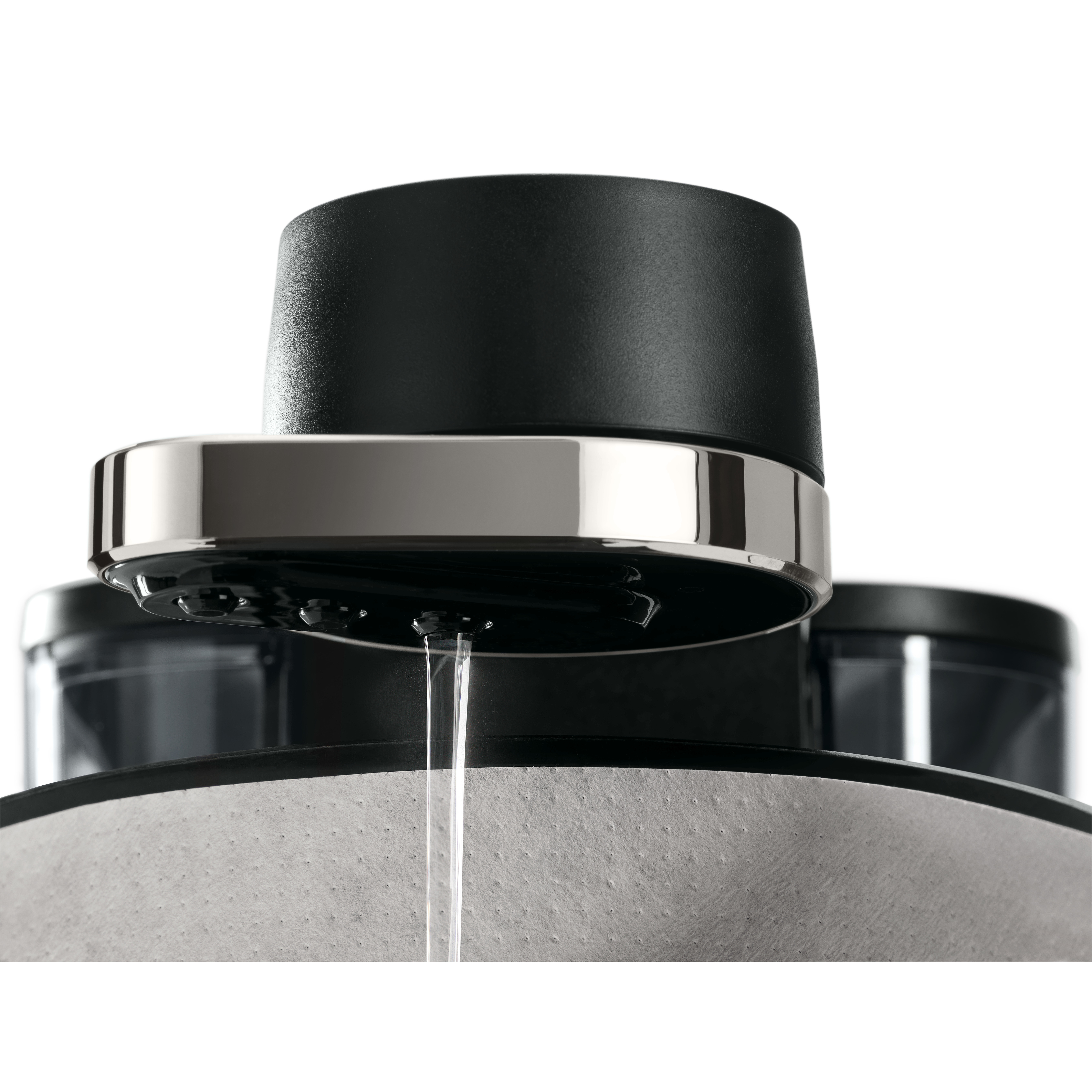 Zbliżenie ekspresu do kawy. Woda wypływa z wylewki. Widoczne czarne i srebrne elementy.