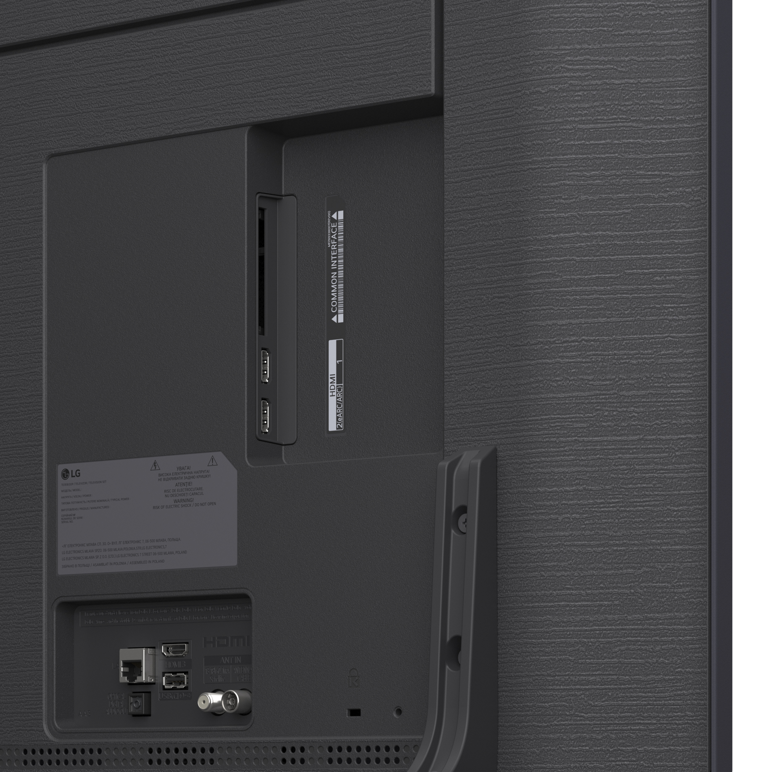 Zbliżenie tylnego panelu telewizora z portami, etykietami i teksturowaną, ciemnoszarą powierzchnią.