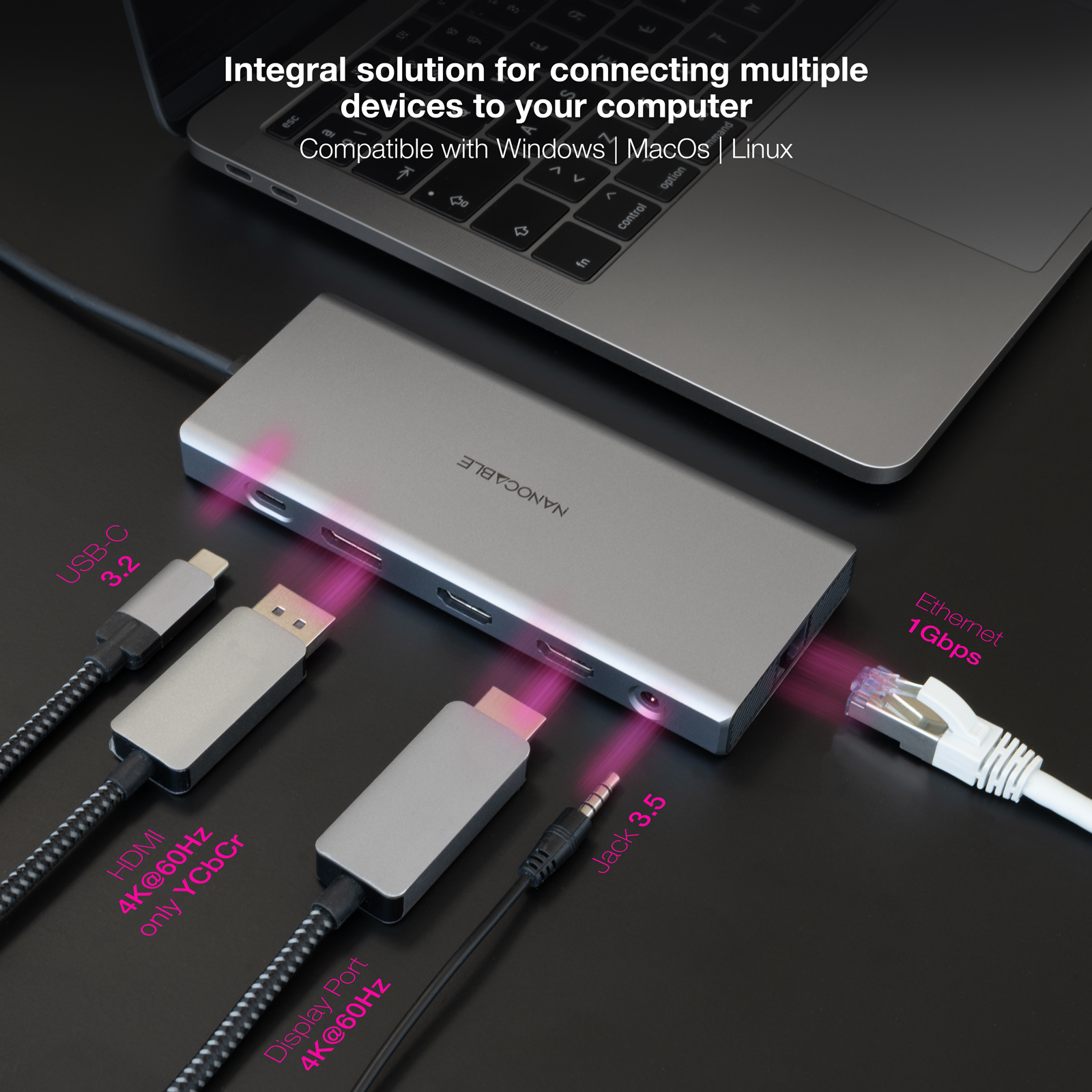 Un hub argentato con cavi collegati: USB-C, HDMI, DisplayPort ed Ethernet, accanto a un laptop.