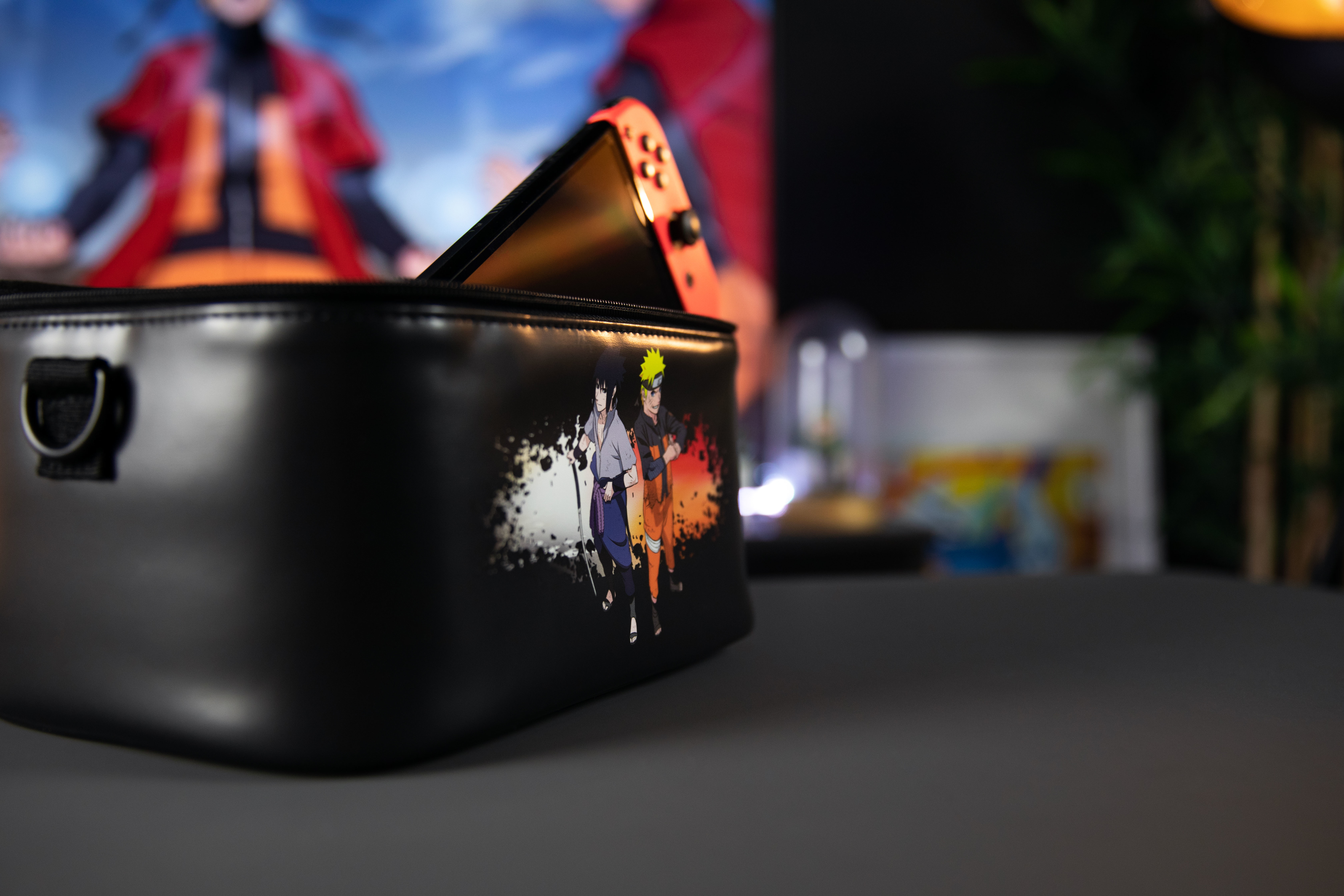 Czarna torba z postaciami z anime. W środku jest Switch. Tło jest rozmyte. Ostrość skupia się na torbie.