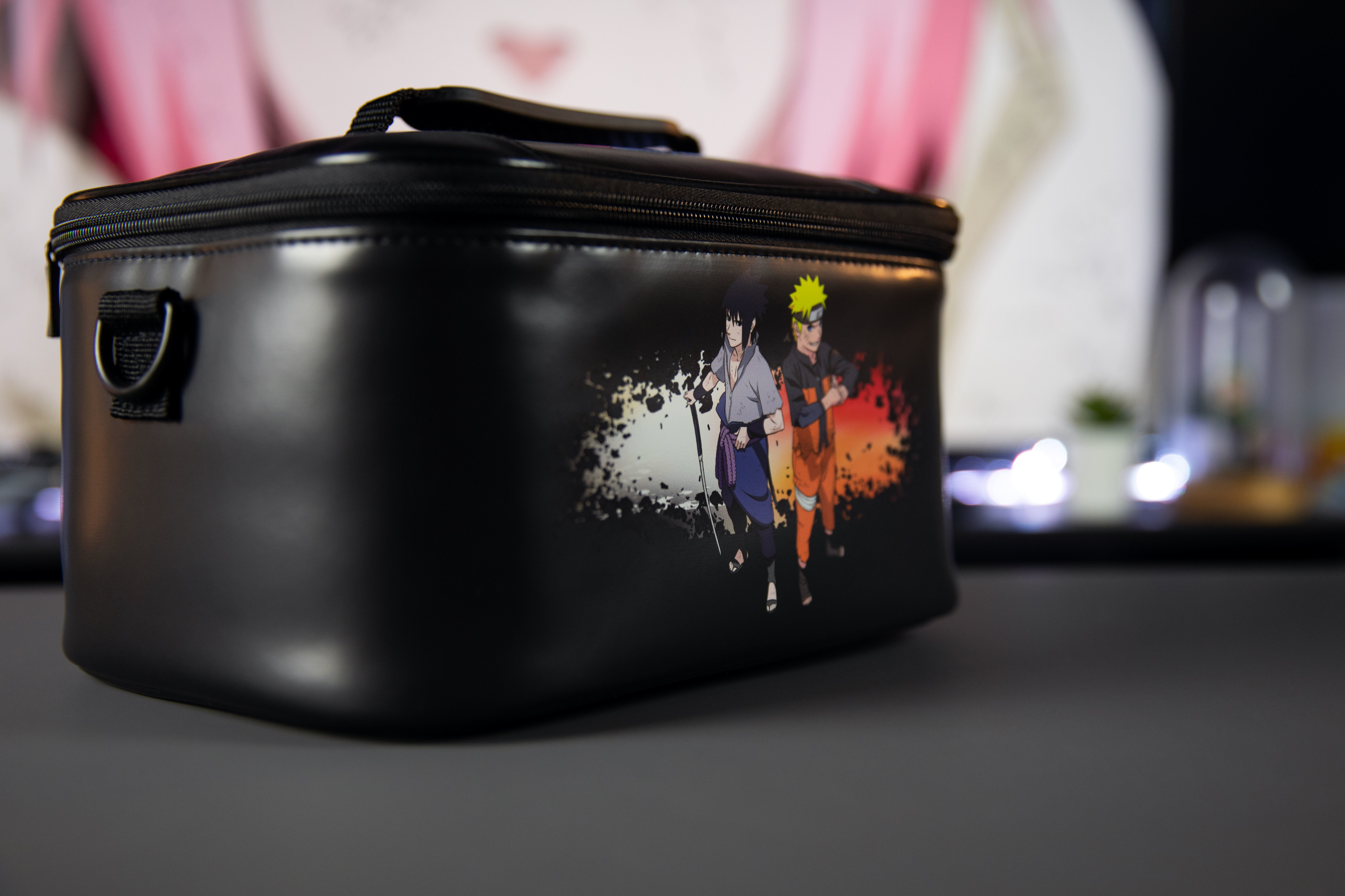 Czarna torba z grafiką Naruto na stole. Tło jest rozmyte.
