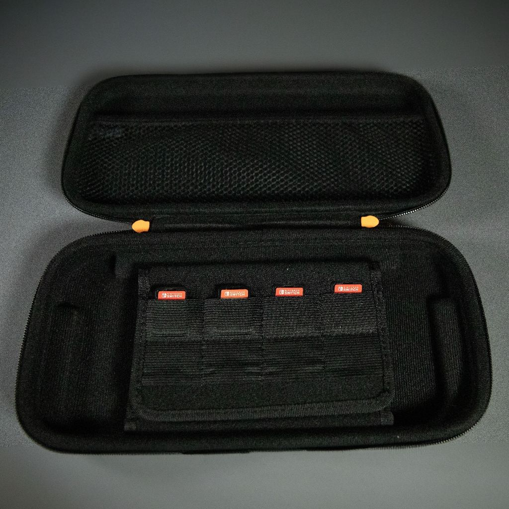 Open black Nintendo Switch case. Inside, there are game cartridges and slots. The case is on a gray surface.