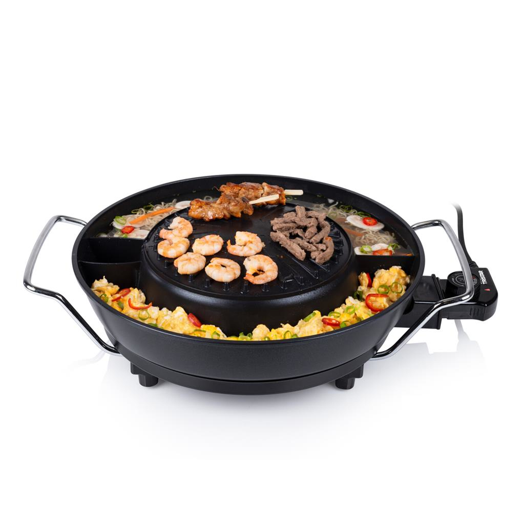 Zwarte elektrische grill met ingebouwde compartimenten. Bevat garnalen, vlees, groenten en noedels. Witte achtergrond.