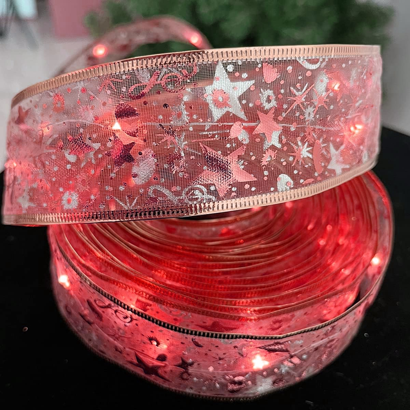 Nahaufnahme eines aufgerollten Bandes mit eingebauten Lichtern. Das Band ist rosa mit Sternmustern, einige Lichter sind an.