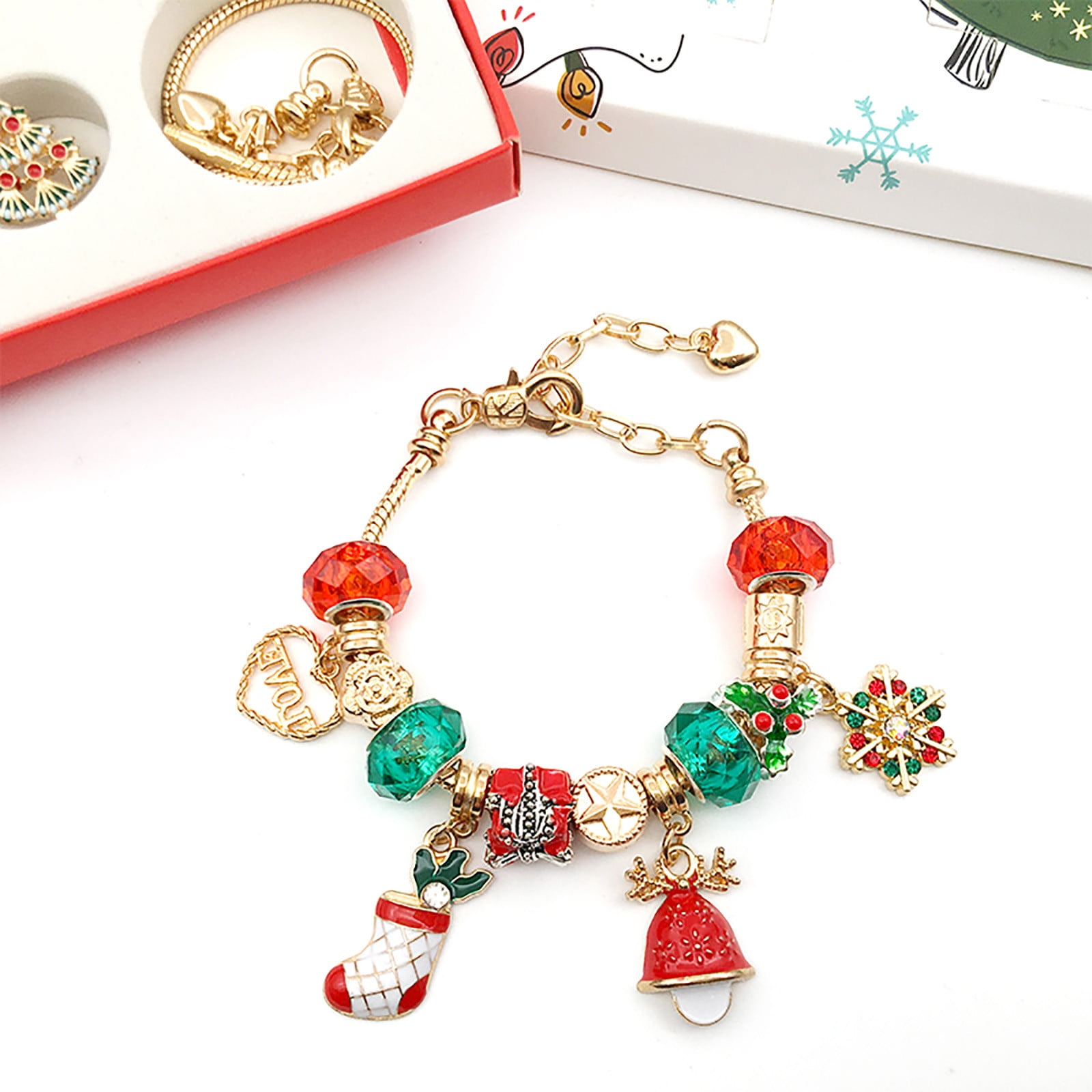 Ein goldfarbenes Weihnachtsarmband mit roten und grünen Anhängern, darunter Perlen, ein Schneeflocke, eine Glocke und ein Strumpf.