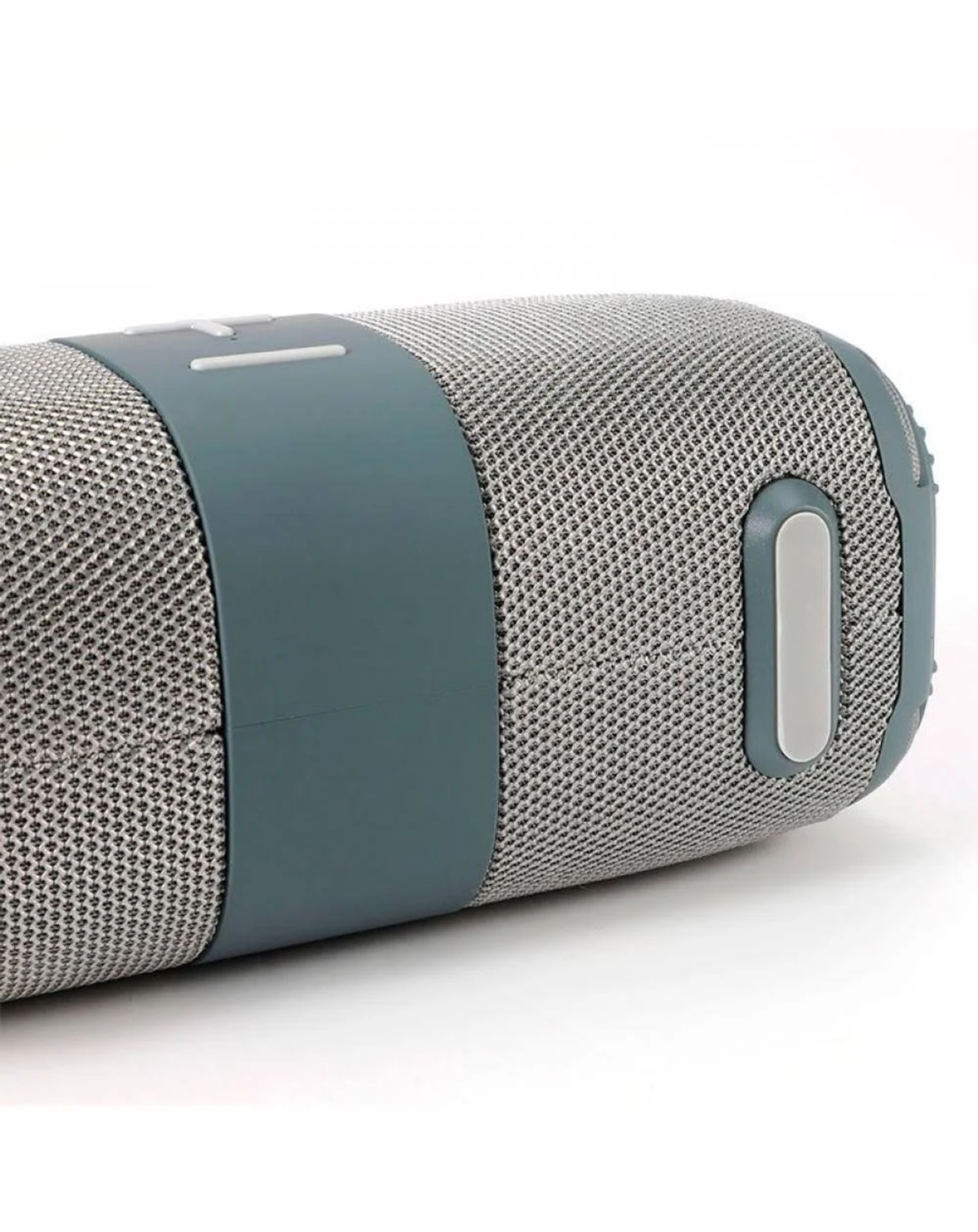 Un altavoz cilíndrico gris y verde azulado se encuentra sobre una superficie blanca. Tiene una textura de malla y botones de control en la parte superior.