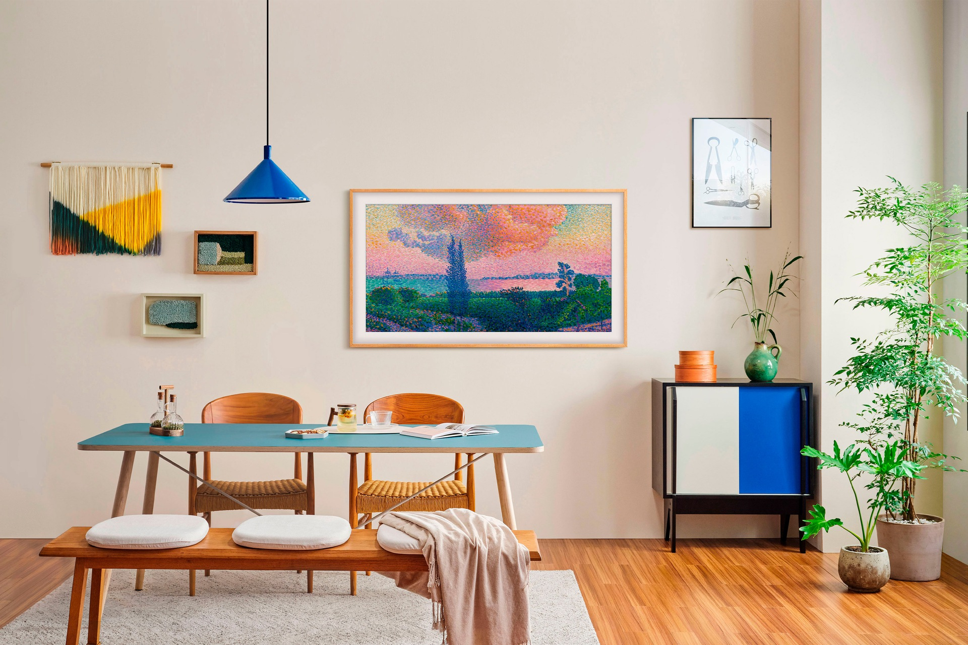 Jadalnia ze sztuką i meblami. Niebieski stół, drewniana ławka i szafka. Dzieła sztuki na ścianie obejmują oprawiony obraz i inne elementy dekoracyjne.