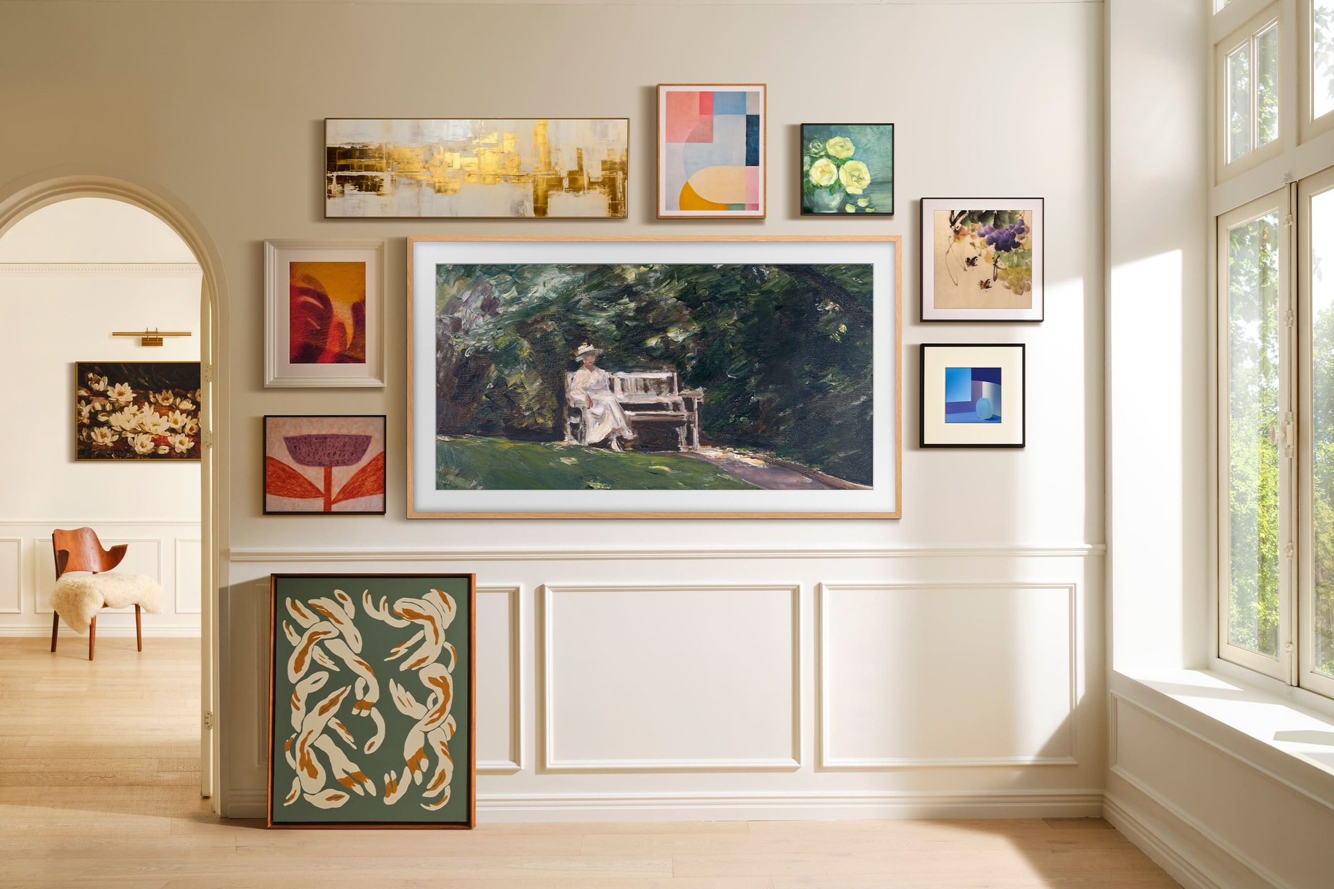 Na ścianie wystawione są różne oprawione dzieła sztuki, w tym obrazy i abstrakcyjne elementy. Kobieta siedzi na ławce w parku.