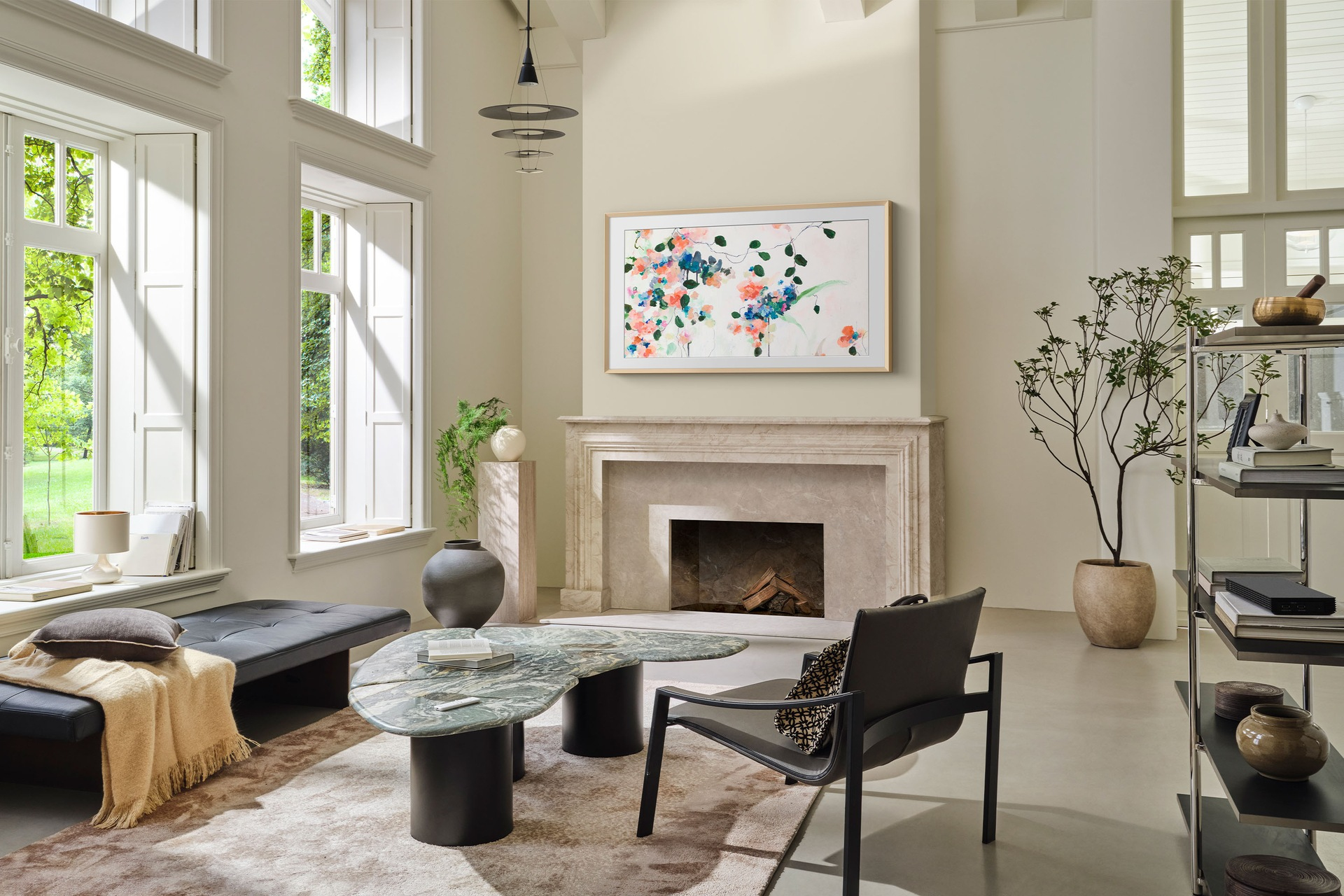 Salon z kominkiem, obrazem, designerskimi meblami, oknami i dywanem. Kolory są neutralne.