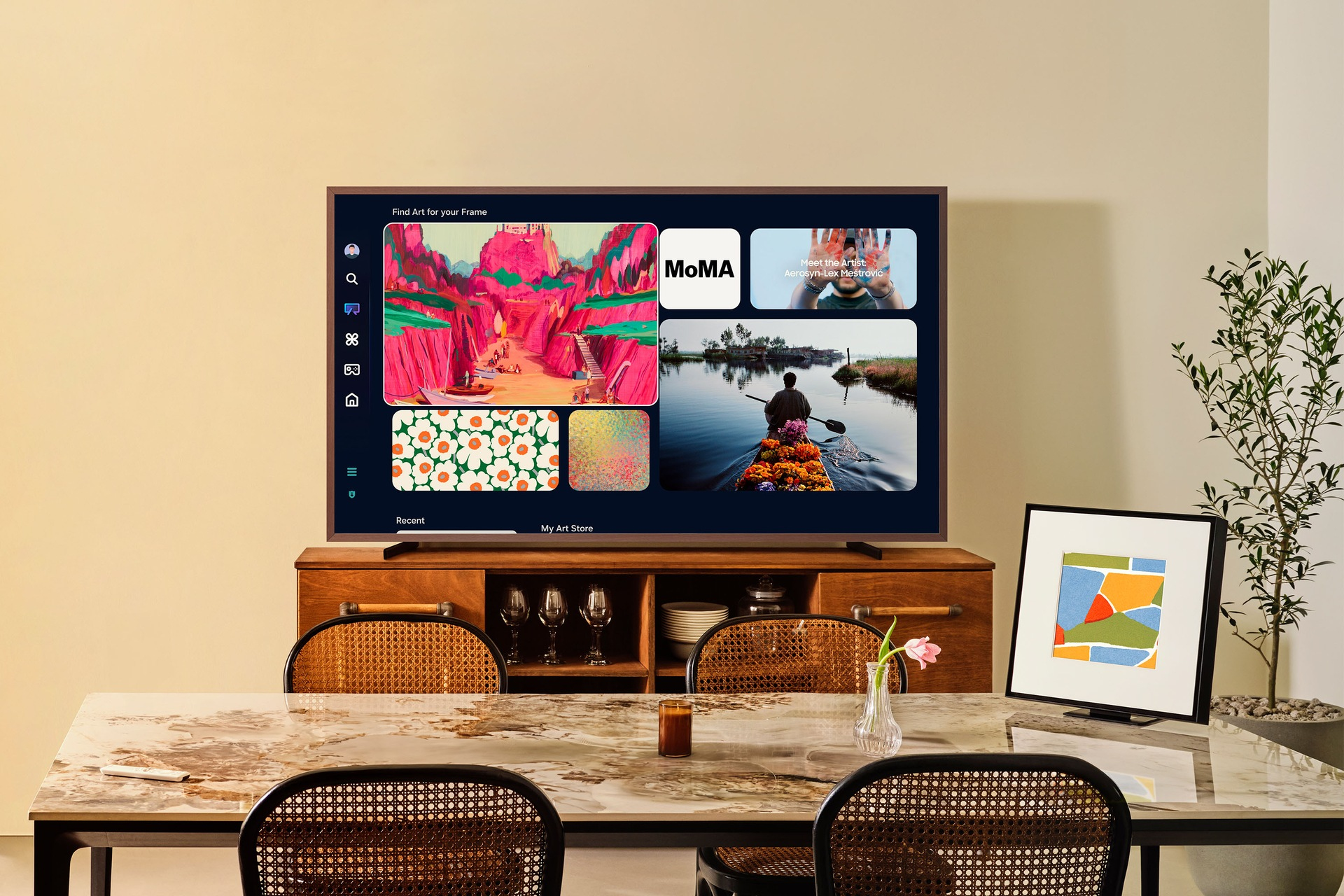 Nowoczesny salon z dużym telewizorem wyświetlającym sztukę. Stół z krzesłami, oprawione dzieło sztuki i roślina na pierwszym planie.