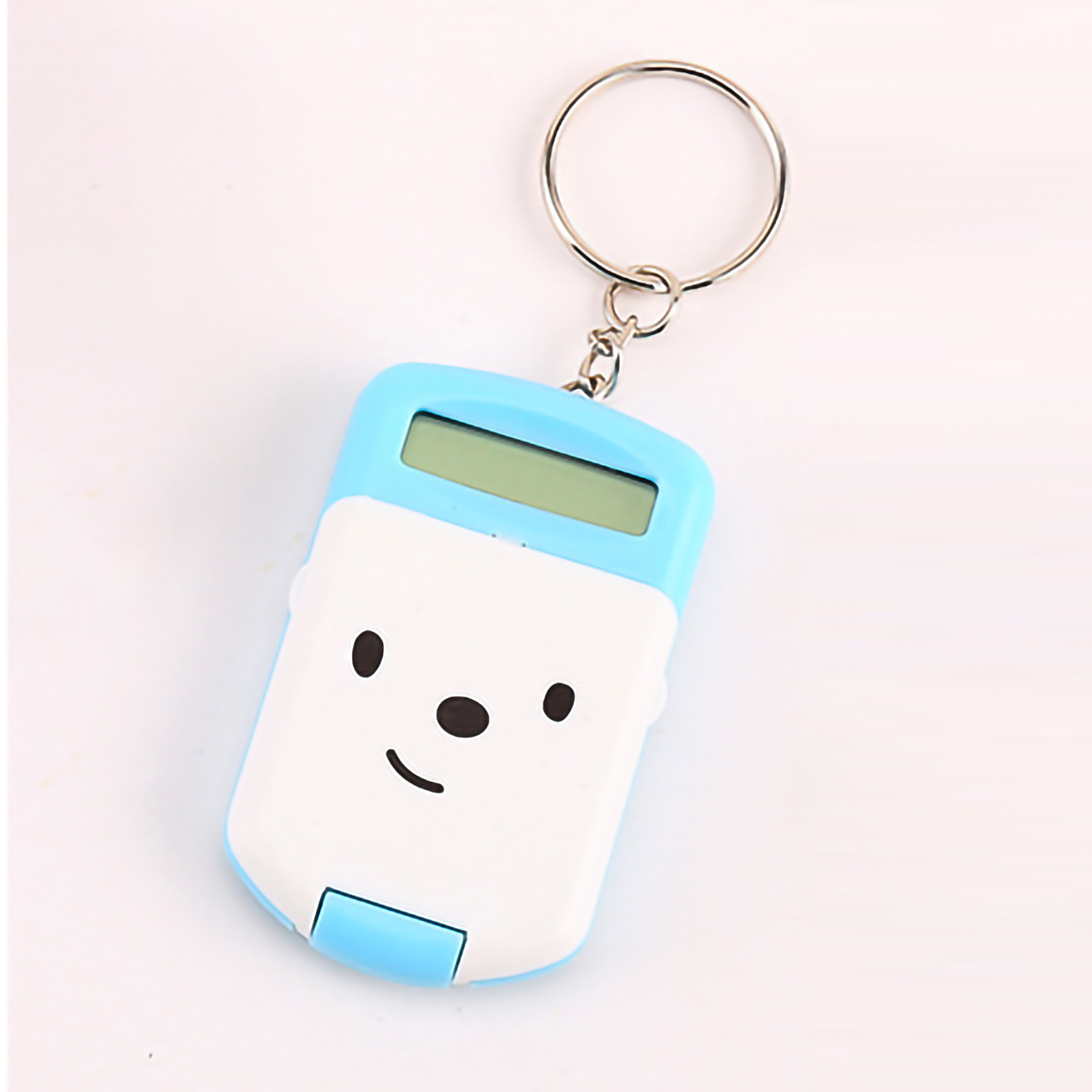 Ein blau-weißer Taschenrechner-Schlüsselanhänger mit einem Smiley-Gesicht. Er hat einen Metallring. Der Hintergrund ist weiß.