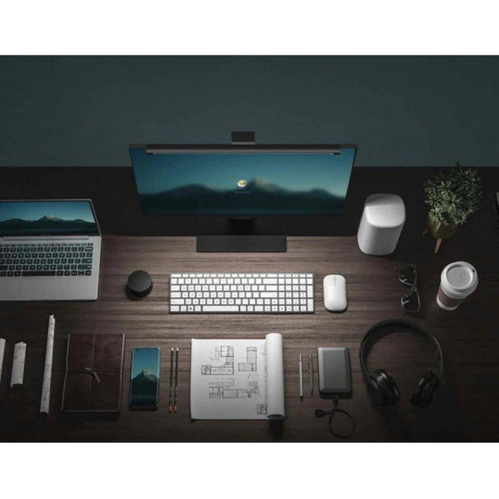 Schreibtisch-Setup mit Laptop, Monitor, Tastatur, Maus, Kopfhörern und anderem Zubehör auf einer Holzoberfläche.