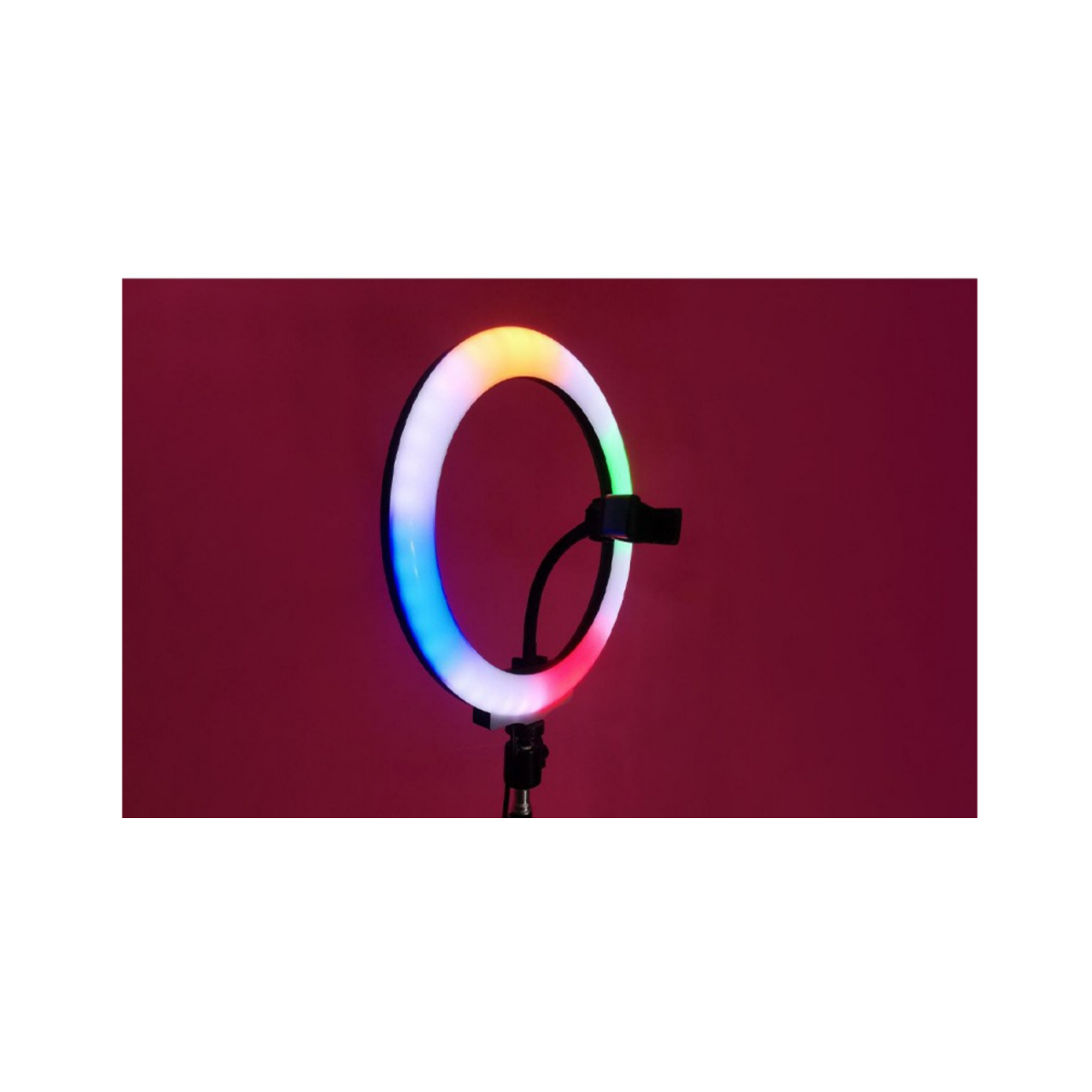 Ein Ringlicht mit Regenbogenfarben steht auf einem Ständer vor rotem Hintergrund. Das Licht ist an und eine Telefonhalterung ist befestigt.
