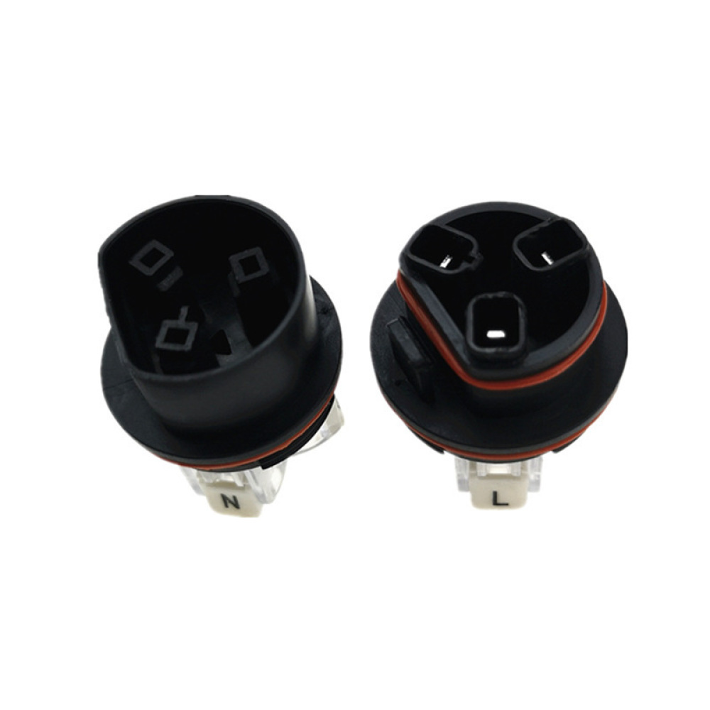 Zwei schwarze elektrische Stecker mit jeweils drei Löchern, einer mit der Aufschrift 'N' und der andere 'L', vor weißem Hintergrund.