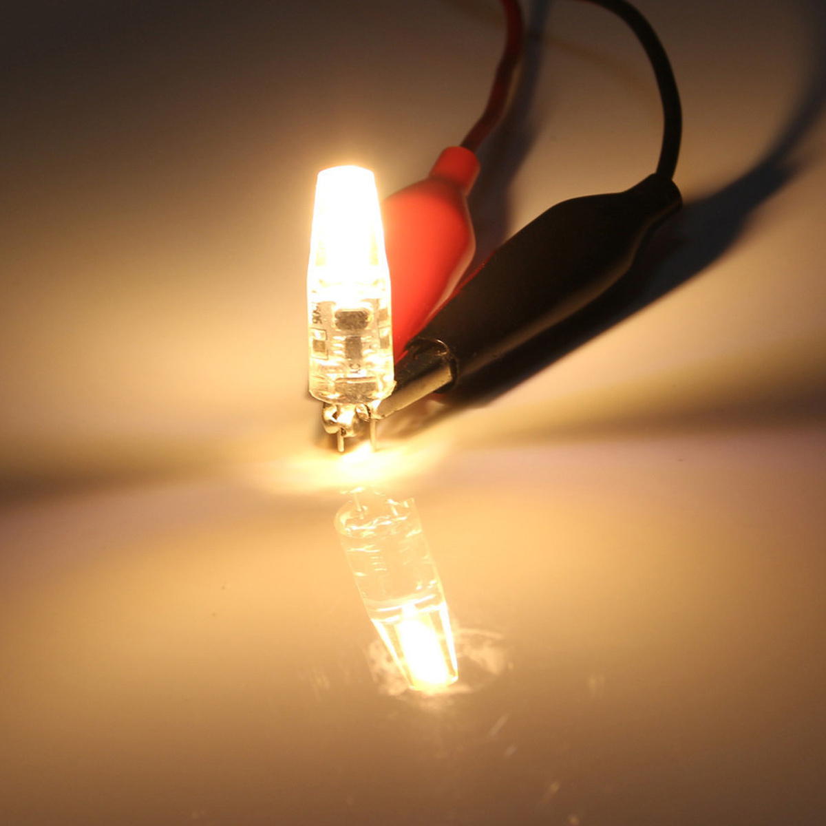 Eine leuchtende LED-Glühbirne mit roten und schwarzen Drähten. Die Glühbirne ist hell und spiegelt sich auf der Oberfläche.
