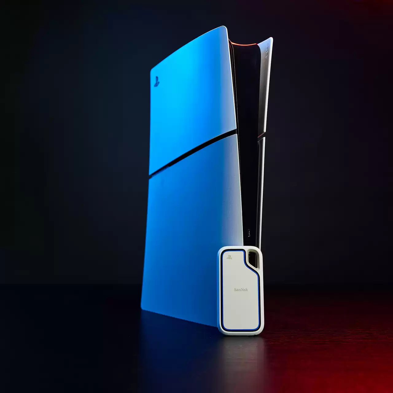 Niebieska konsola PlayStation 5 i białe zewnętrzne urządzenie pamięci masowej SanDisk na odblaskowej powierzchni, ciemne tło.