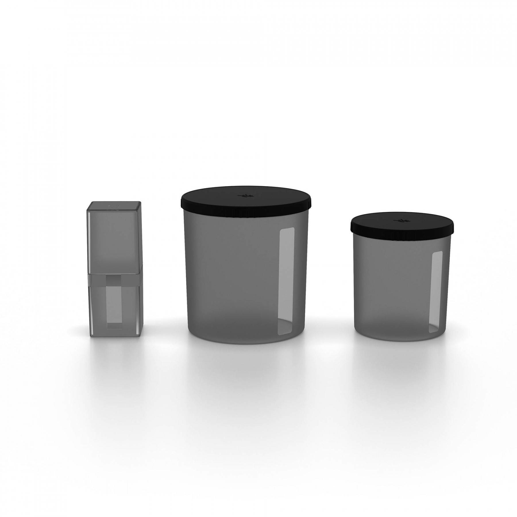 Trzy przezroczyste szare pojemniki z czarnymi pokrywkami stoją na białej powierzchni. Jeden jest prostokątny, dwa cylindryczne.